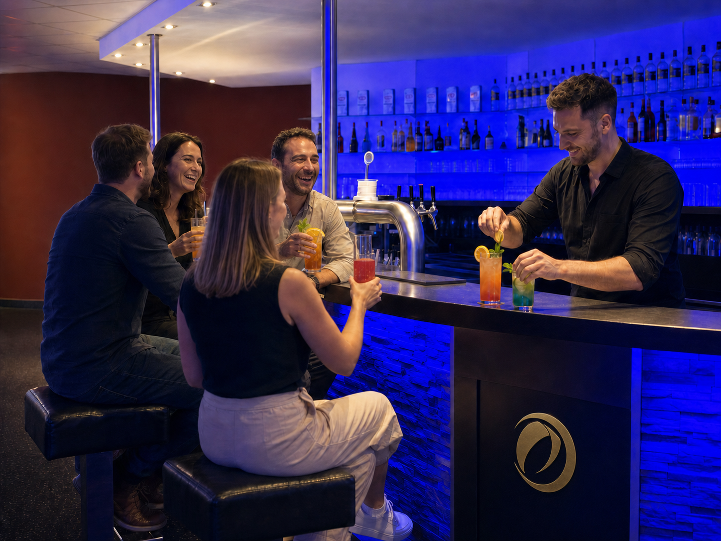 A bartender garnishes drinks for four guests at a blue-lit bar.