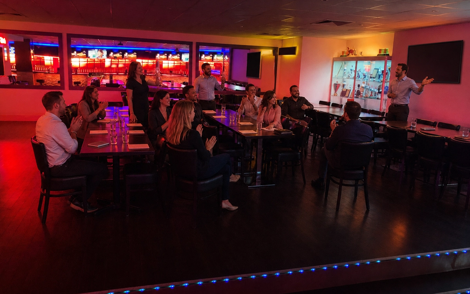 A group listens to a presentation in a lit event area.