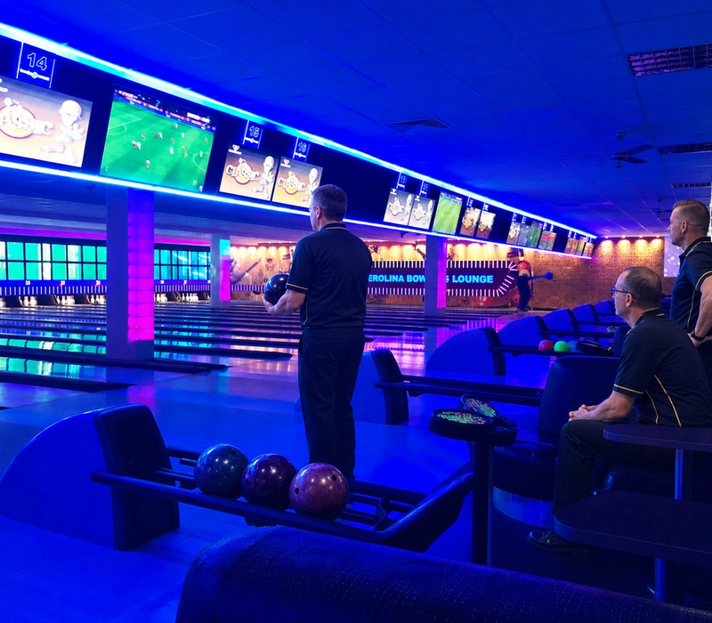Three adult sport bowlers prepare for their game beside the lanes.