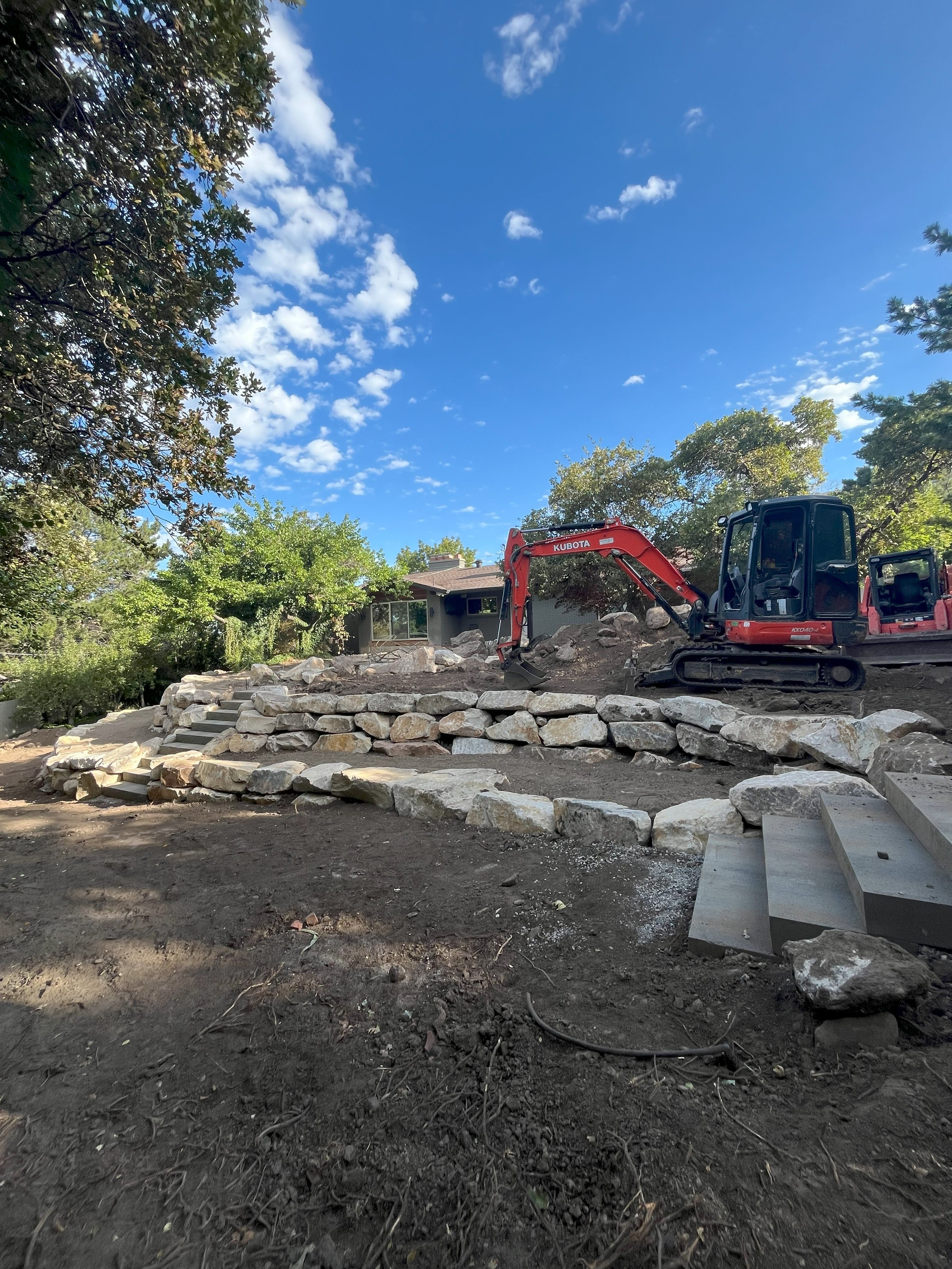 Tiered boulder retaining wall taking shape during Holladay landscape project.