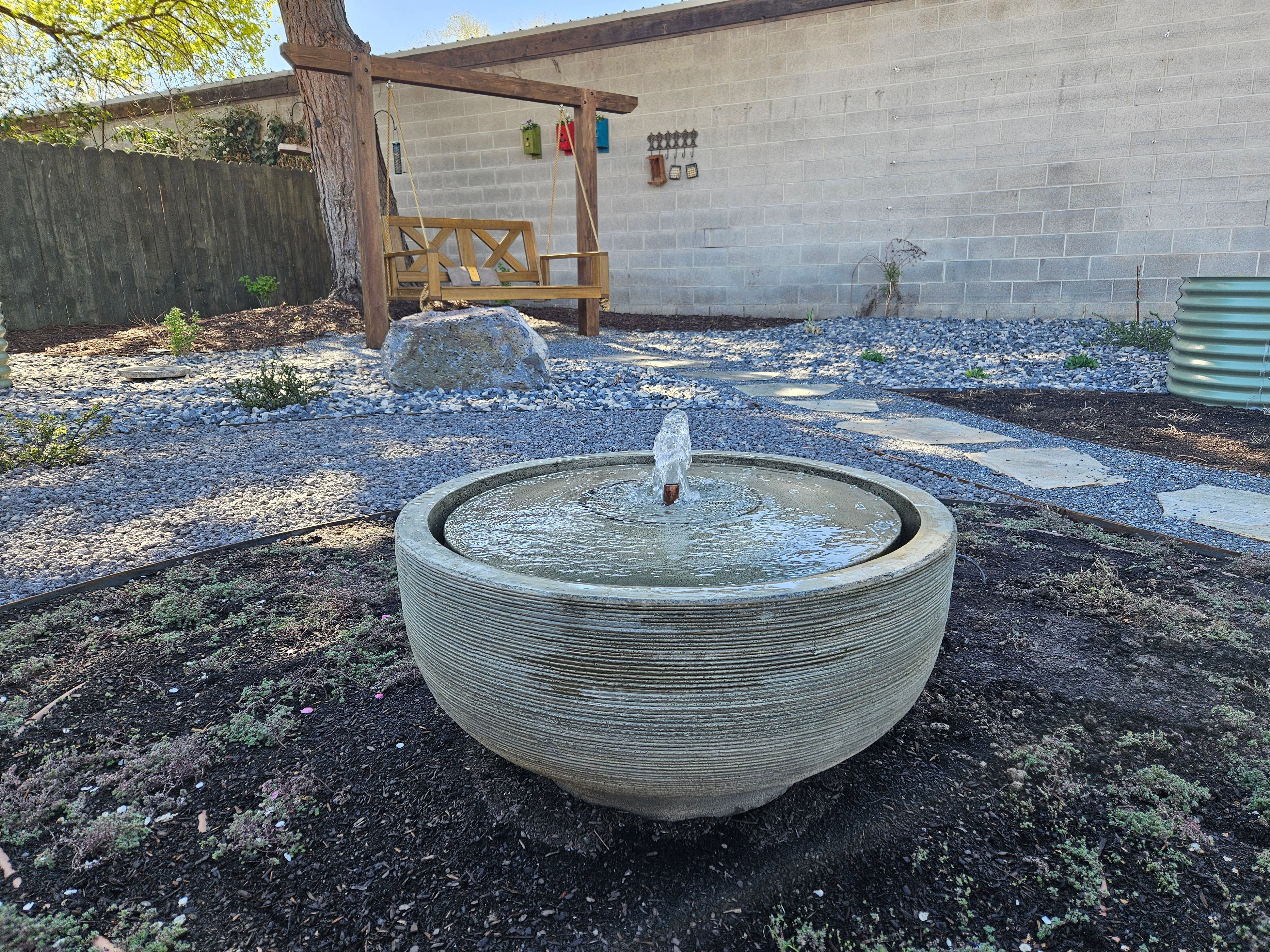 Custom water feature fountain surrounded by stone and greenery in a Murray, Utah landscape