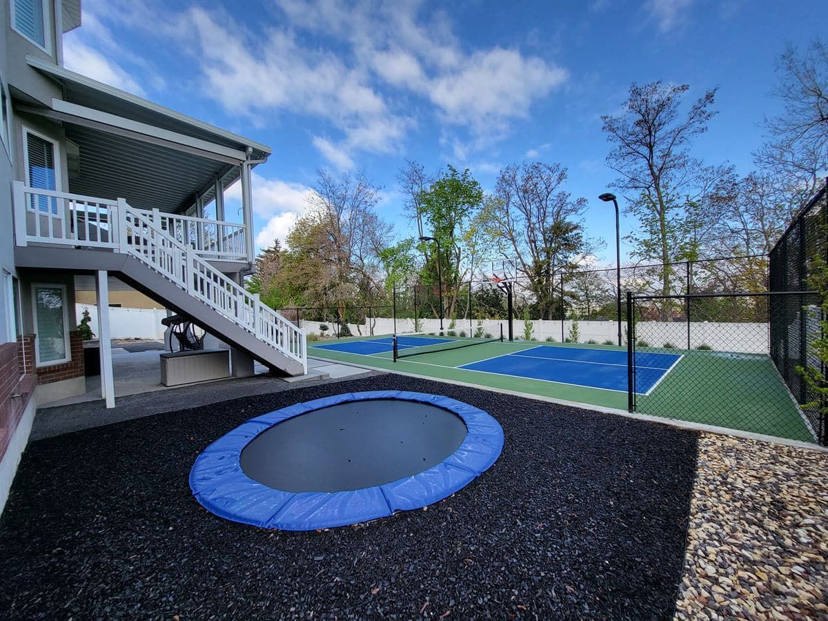 In-ground trampoline and backyard pickleball court in a custom Bountiful landscape design.