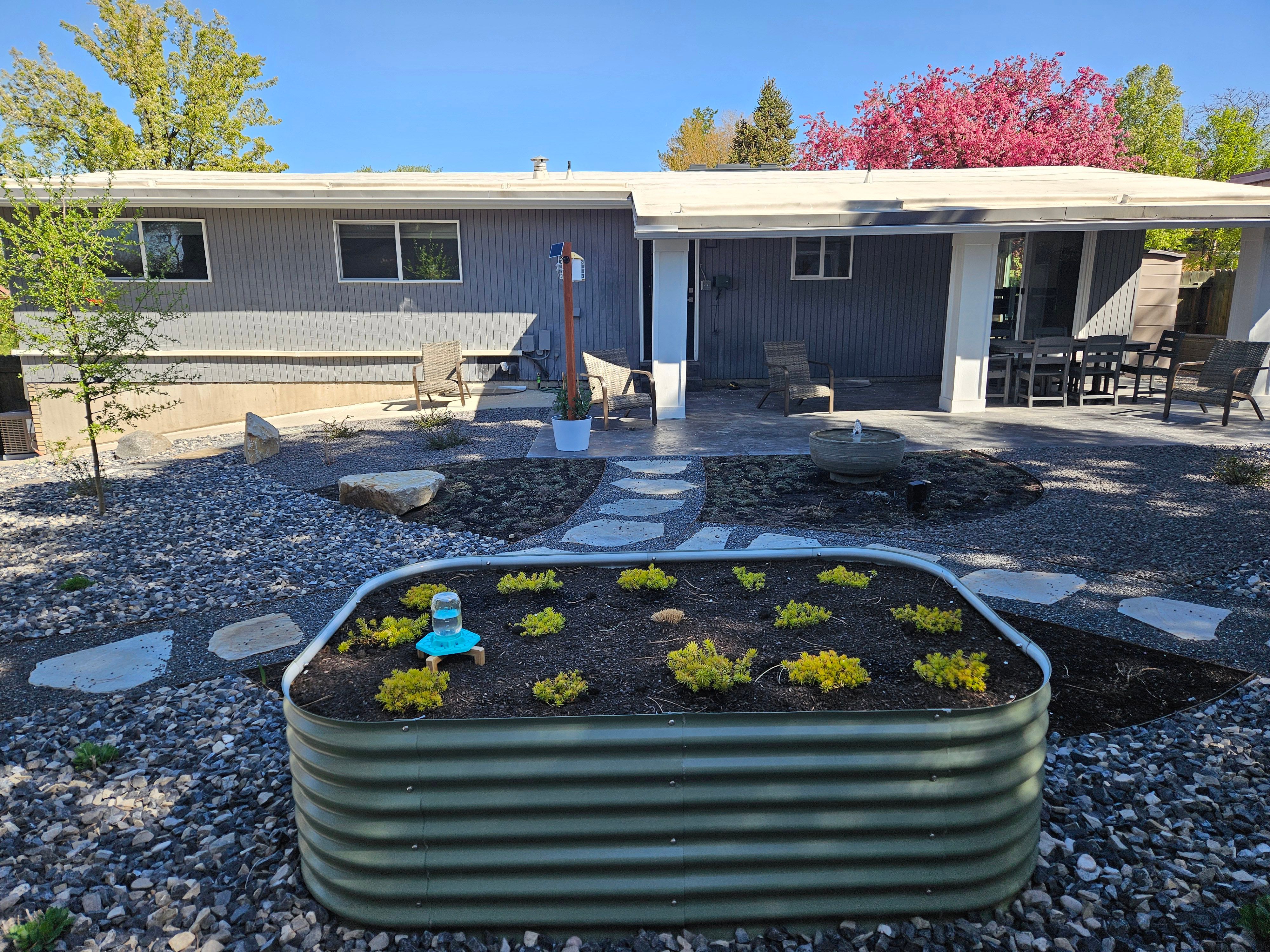 Alternate view of a xeriscape design showing layered plantings and clean gravel beds in Murray, Utah.