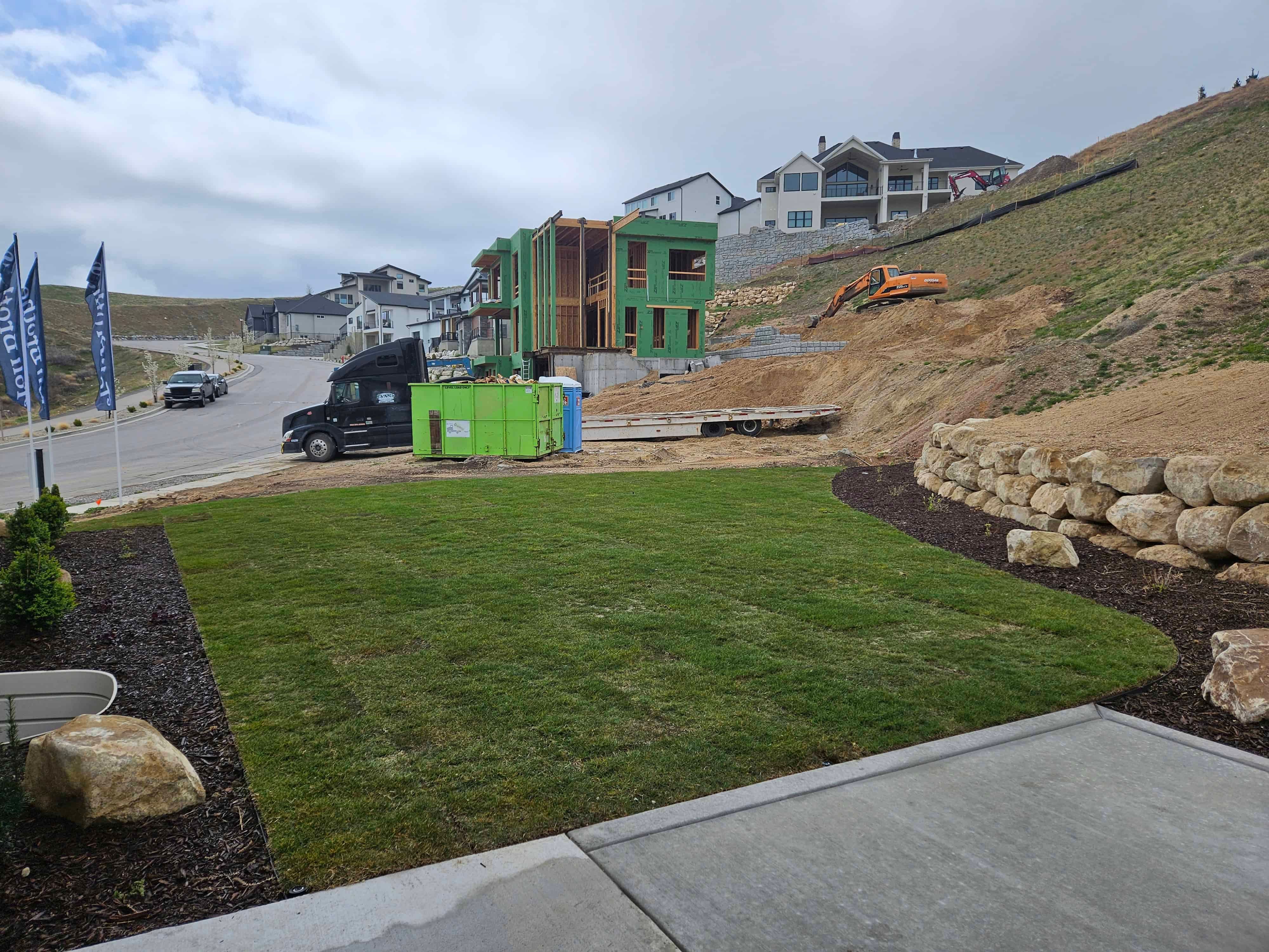 Finished backyard sod and retaining wall installation in Lehi, Utah landscape project.