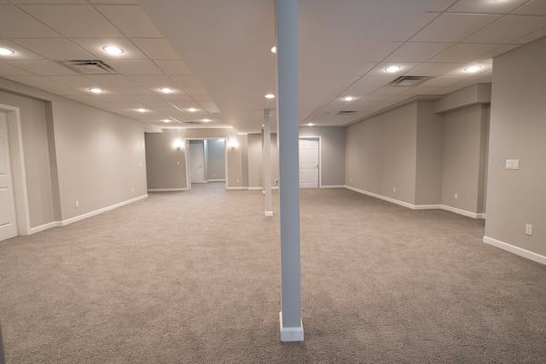 Basement remodeling project in Murray, Utah featuring white carpet, recessed canned lighting, high-quality paint, and additional space achieved through beam installation.