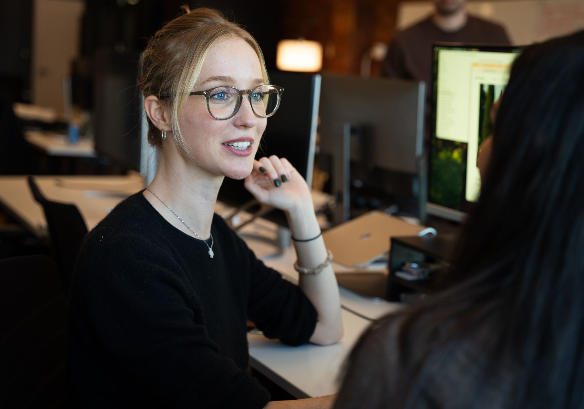 Avallon teammate smiling during a conversation at her desk