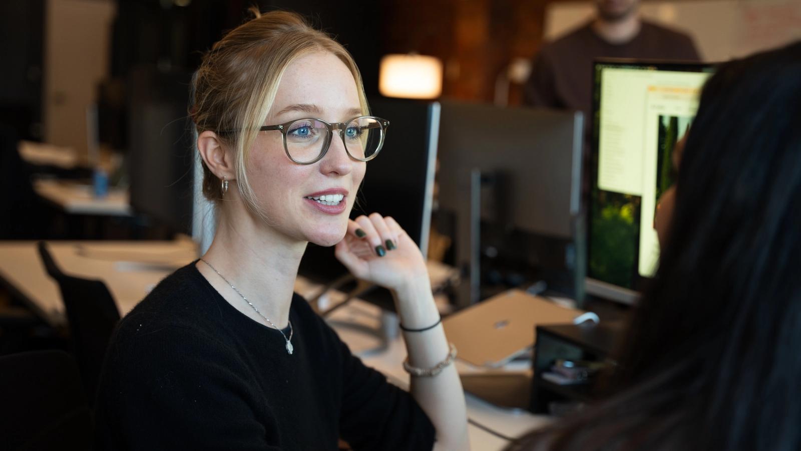 Avallon teammate smiling during a conversation at her desk