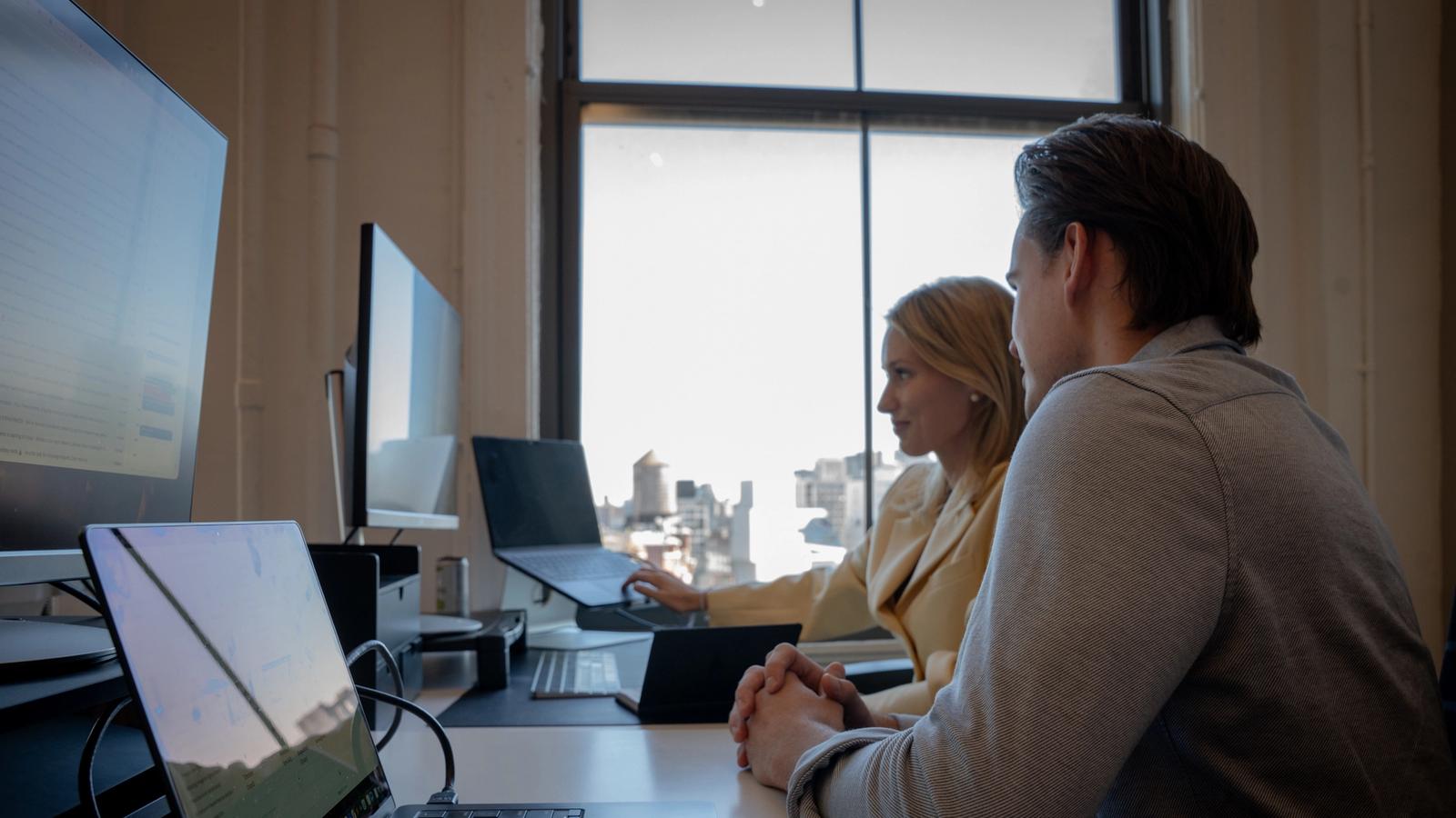 Two Avallon teammates reviewing work by the office window