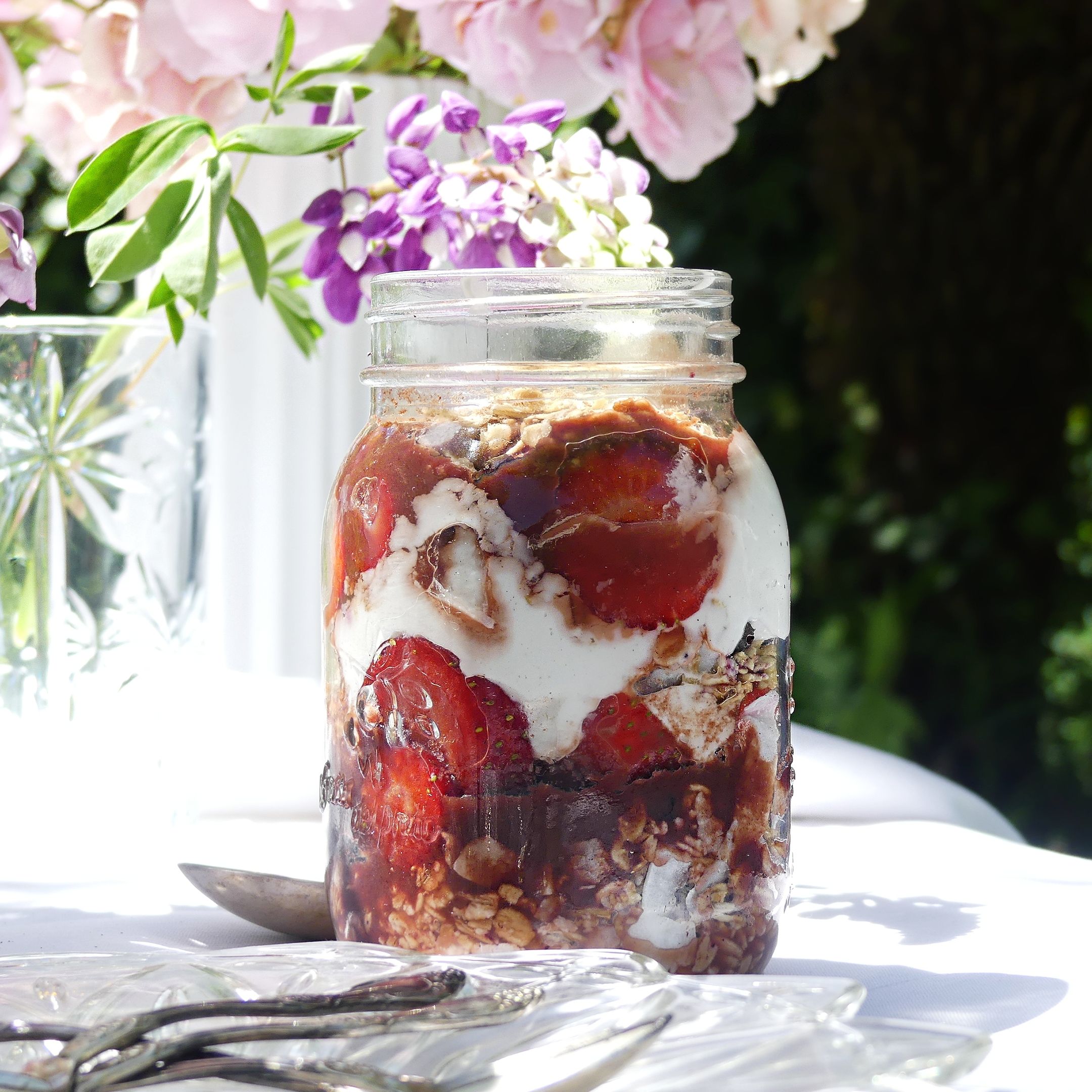 A jar of Queen Garnet Granola with floral backdrop.