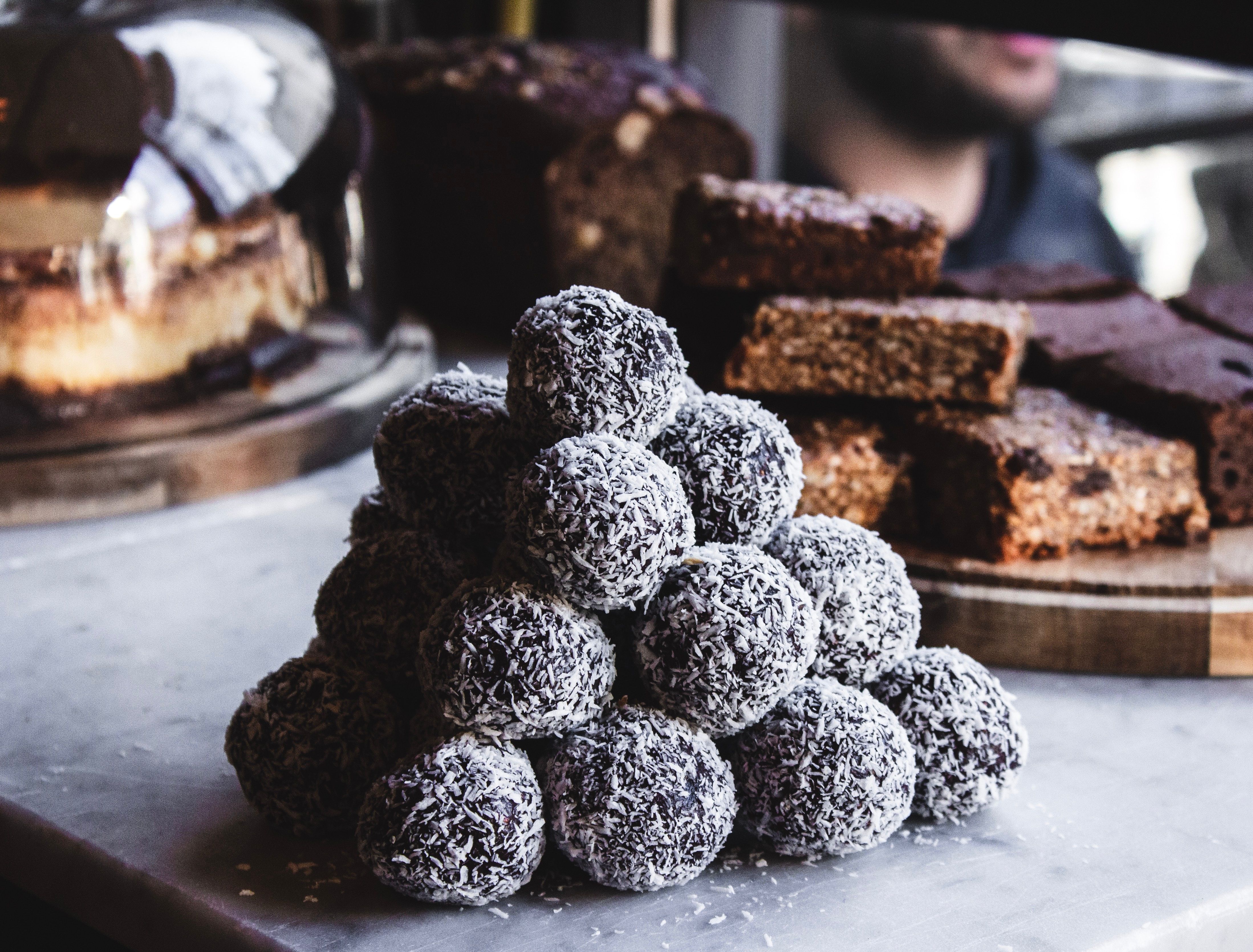 A stacked pile of Queen Garnet plum rum balls on a bench, with other various desserts sitting in the background