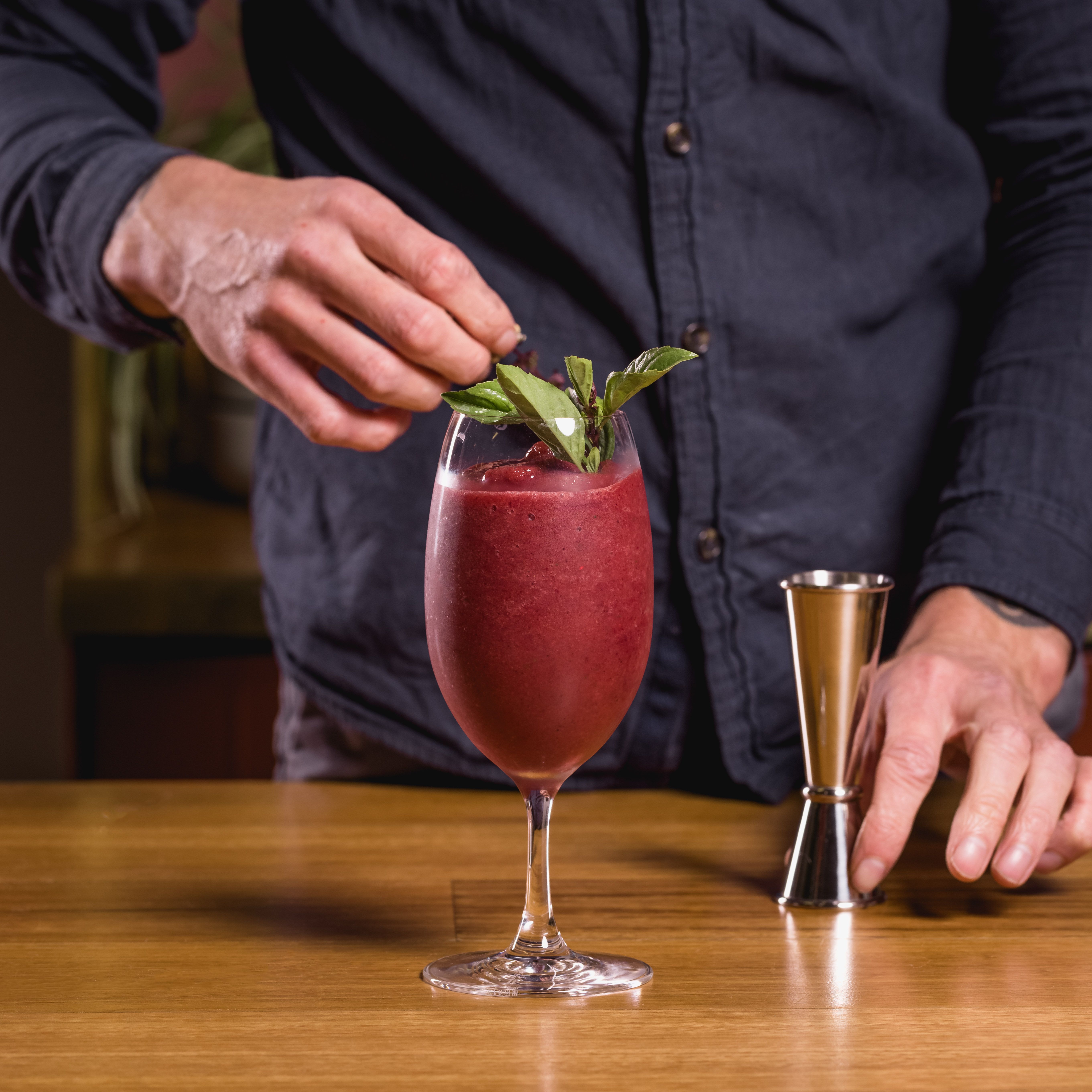 Queen Garnet Nectar of Gods slushie being garnished with thai basil
