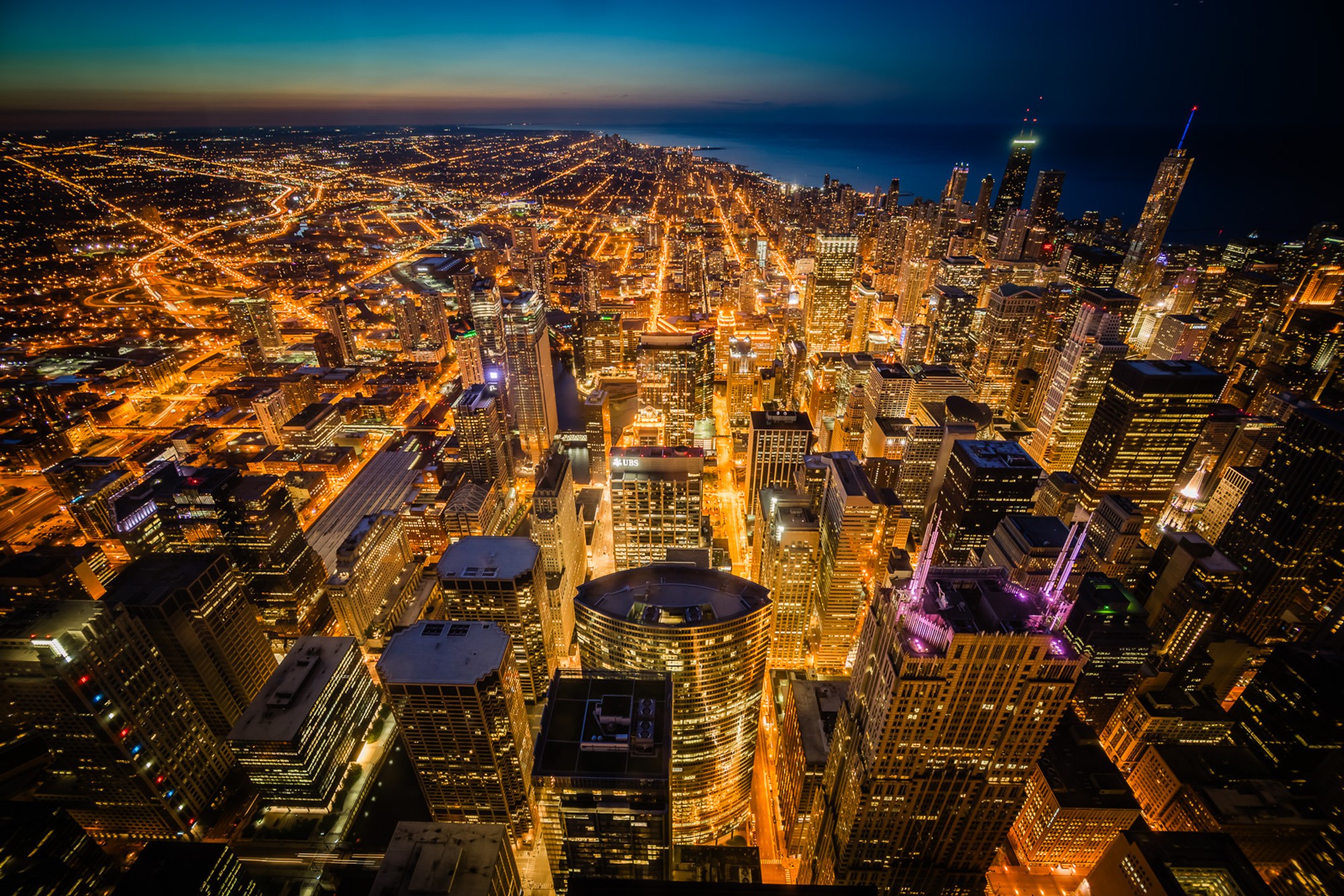 Chicago at night from high above, the illuminated street grid stretching to the horizon. Shot from Willis Tower, the city appears as a dense field of light - the grid that made Chicago the city it became.