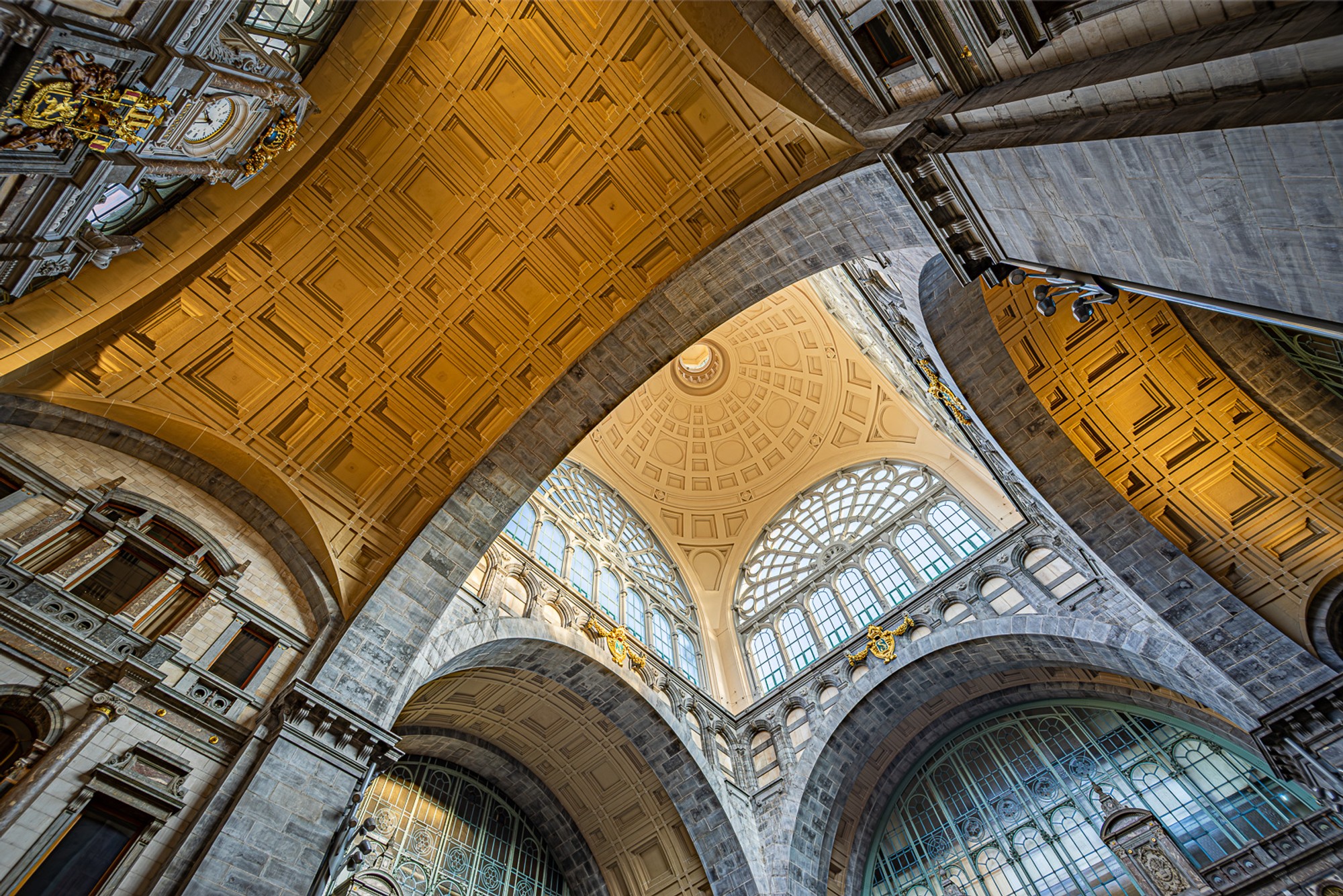 The great dome of Antwerp Central Station photographed from directly below on the platform. Iron ribs and gilded arches radiate outward from the glass crown - one of Europe's finest railway interiors, seen at the angle most passengers miss.