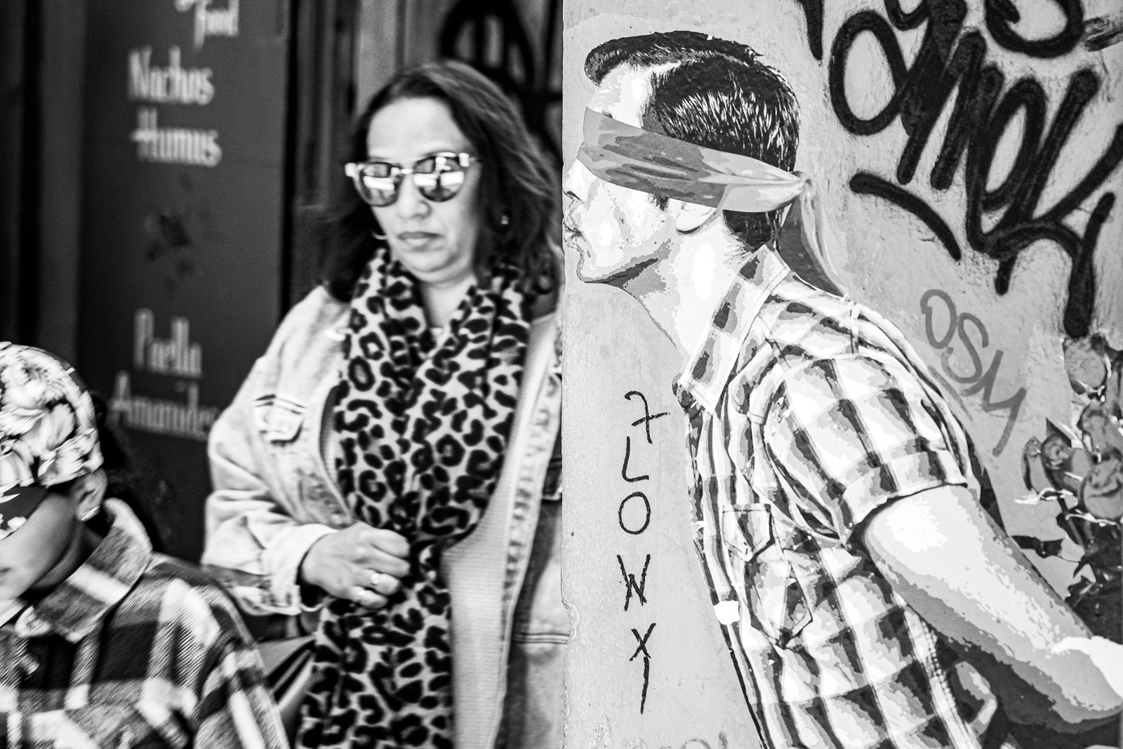Two people on a Barcelona street, 3D meets 2D in black and white. The image is quiet in the way that candid photographs rarely are - something private, held briefly in the frame.