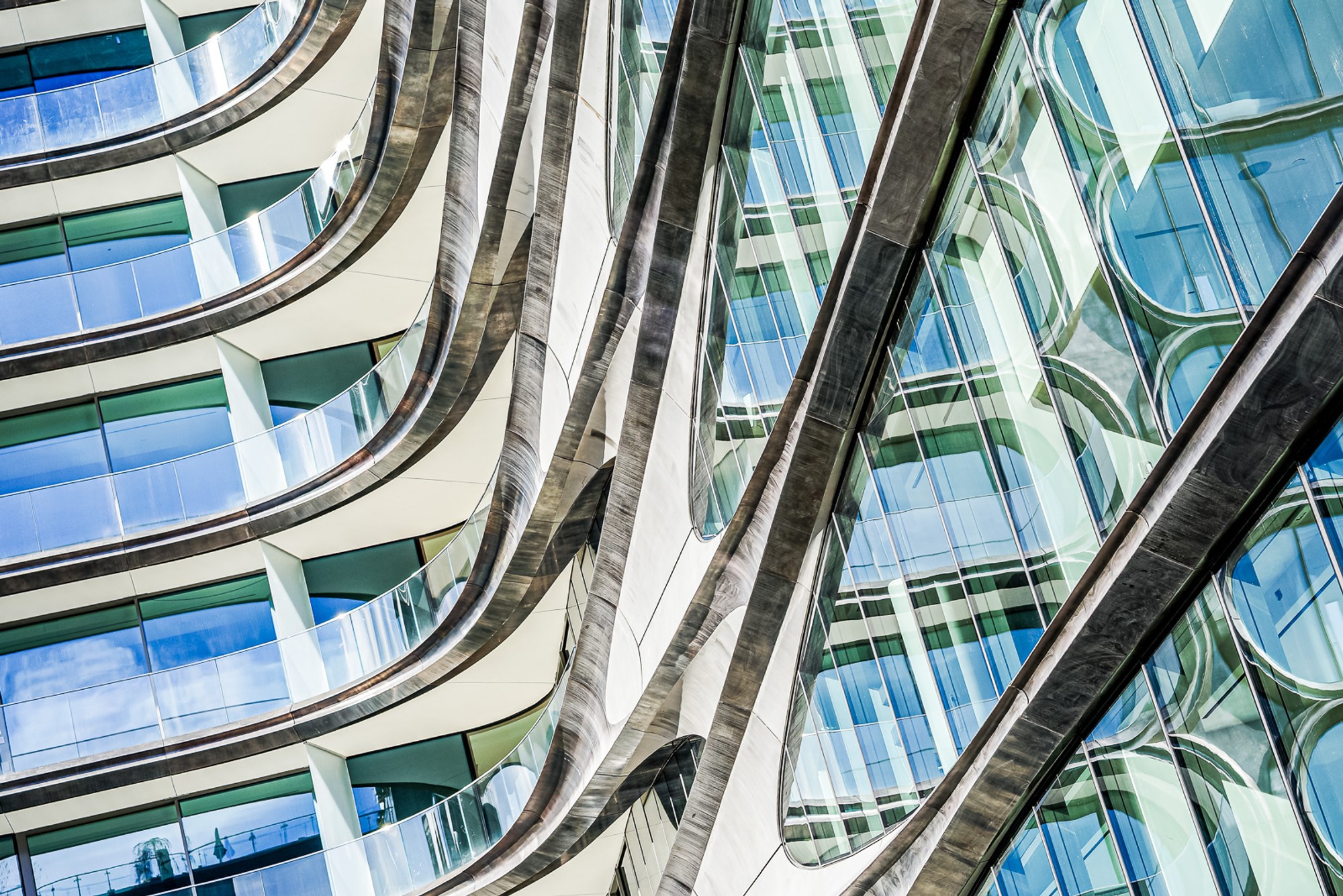 A glass curtain-wall building photographed from the High Line, its curved surface reflecting a distorted version of the surrounding West Side. The building shows everything except itself - the reflection is the architecture.