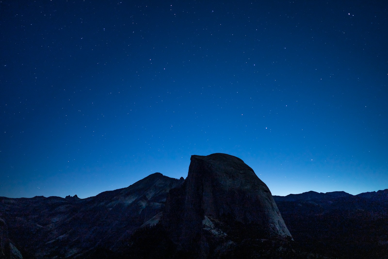 Half Dome in the minutes before sunrise, the granite face still in cold blue shadow, the sky showing the first faint colour at the horizon. The image exists in the brief window before the light changes into something more ordinary.