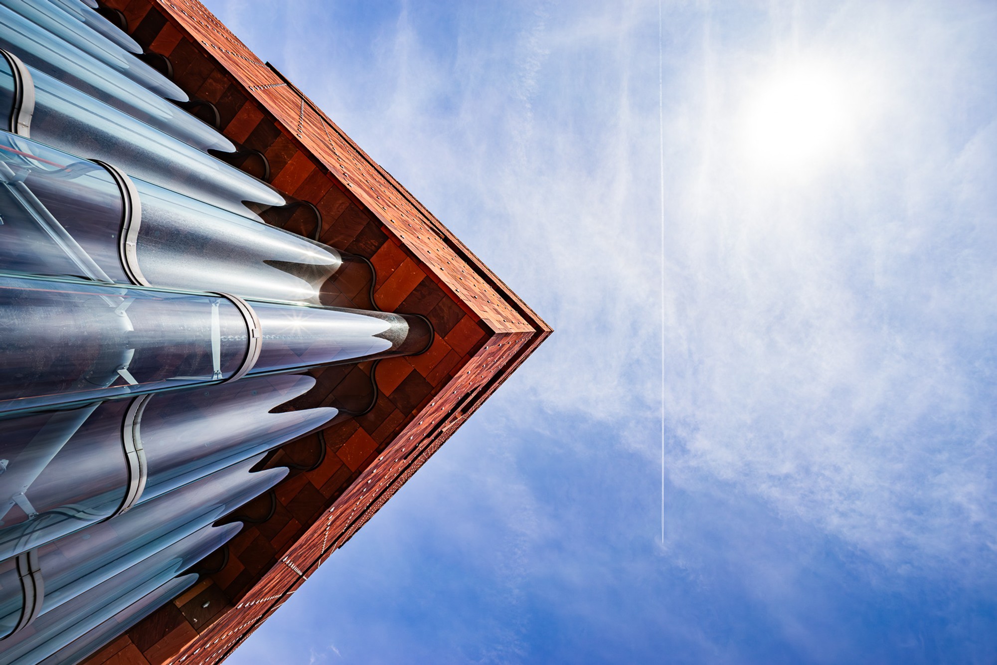 The MAS tower in Antwerp - its stacked, interlocking volumes of red sandstone and glass photographed from below at a sharp upward angle. A building whose unconventional geometry reveals something new from every vantage point.