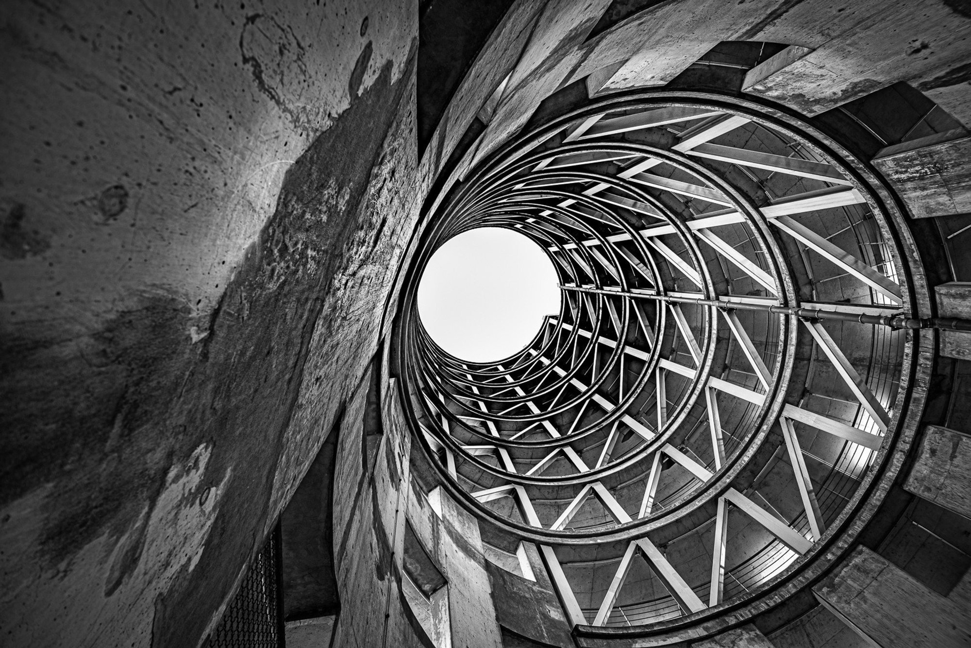 A Cologne parking structure becomes something else entirely when viewed from directly below. The concrete ramp spirals upward in concentric rings toward a single circle of open sky - geometry found inside a building most people drive through without ever looking at.
