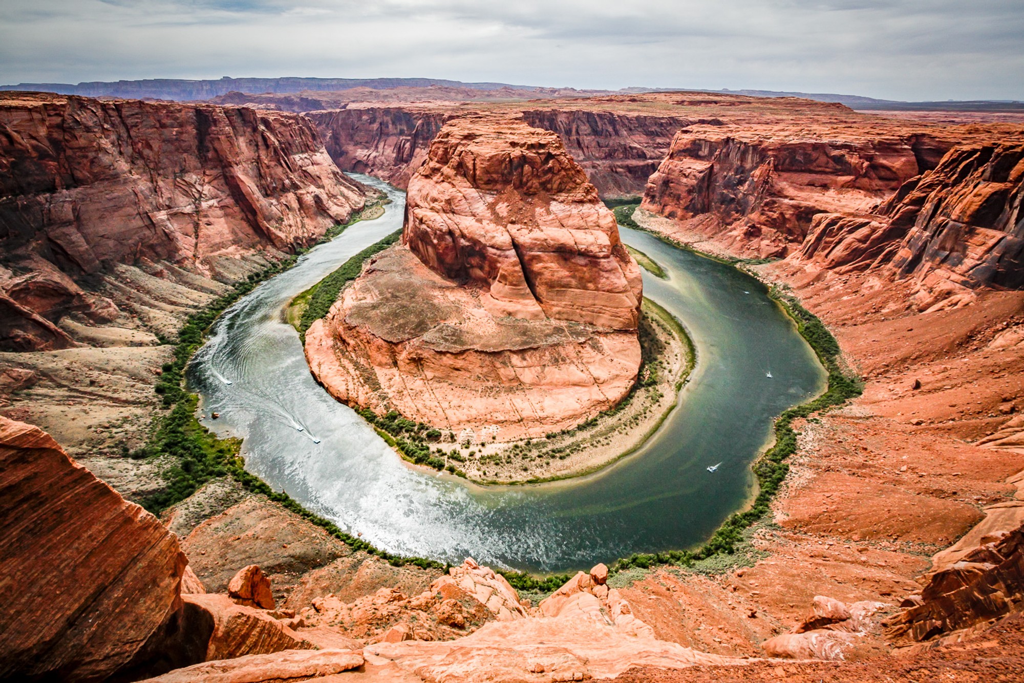 The Colorado River at Horseshoe Bend photographed from the rim looking straight down, the turquoise water making a near-complete circle around the sandstone peninsula. A scale that photographs rarely manage to convey fully - and this one does.