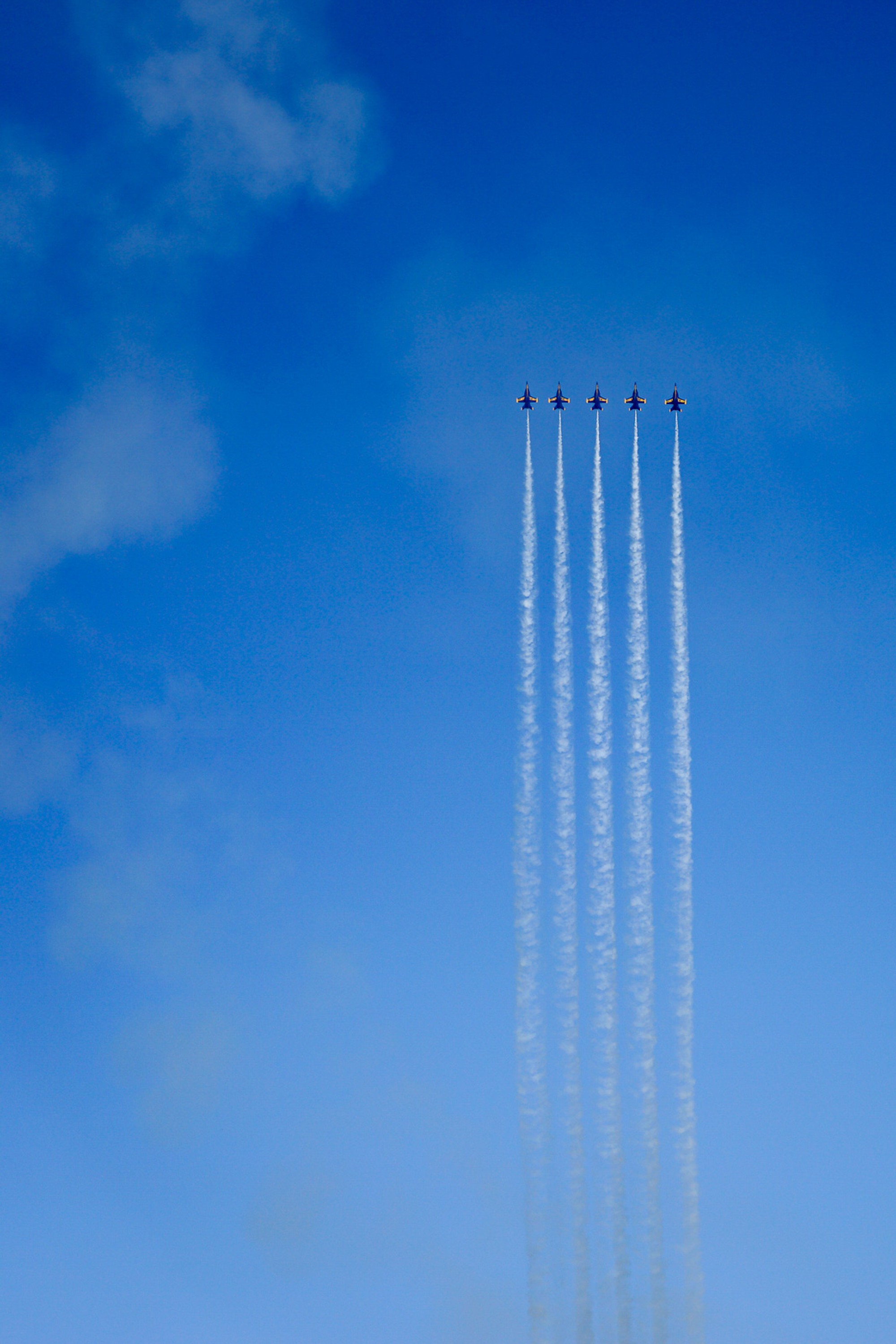 Five Blue Angels in tight formation against a clear California sky, their white contrails tracing the arc of the pass. The precision is such that four aircraft appear almost as one shape - movement and stillness occupying the same moment.