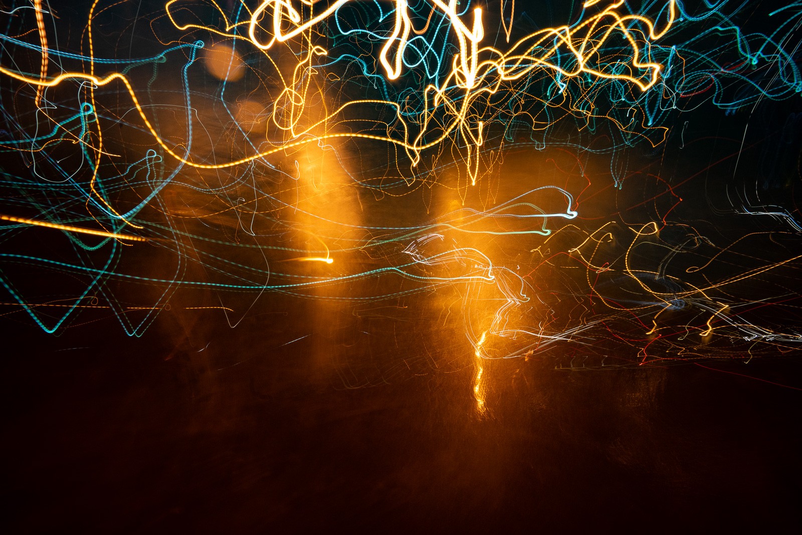 Abstract light painting over New Orleans, a long exposure capturing arcs and trails of orange and gold against darkness. The forms suggest movement without naming it - an image that belongs to its moment and nowhere else.
