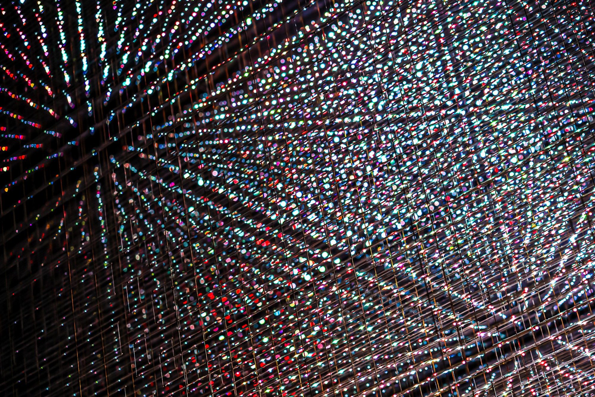 A large LED installation photographed from directly below, its lights arranged in concentric rings of intense colour. The mandala of light fills the ceiling - an image the eye keeps wanting to return to the centre of.
