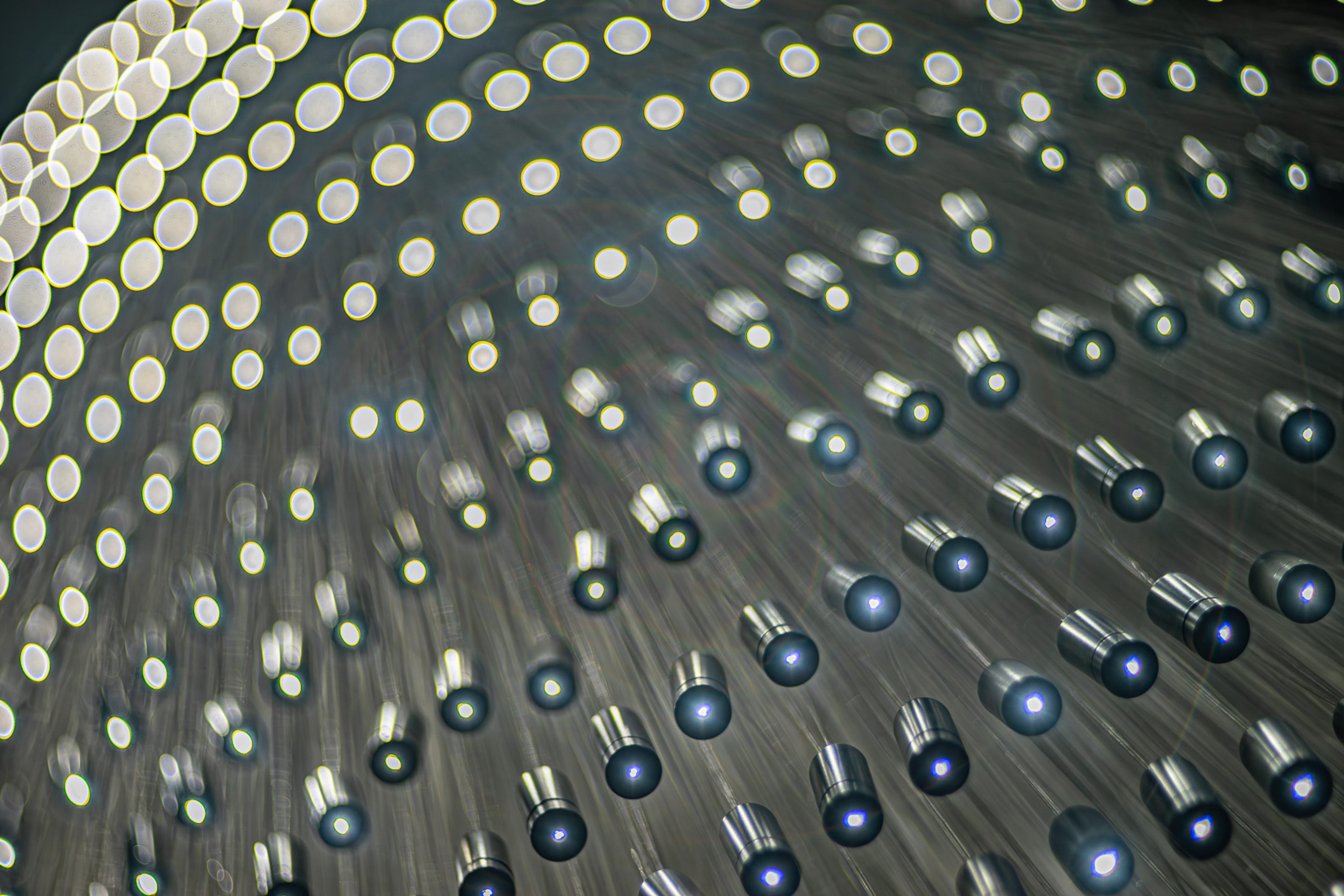 Hundreds of small LEDs suspended on individual wires at varying heights from a Parisian ceiling, photographed from directly below. The aggregate reads as a single luminous cloud