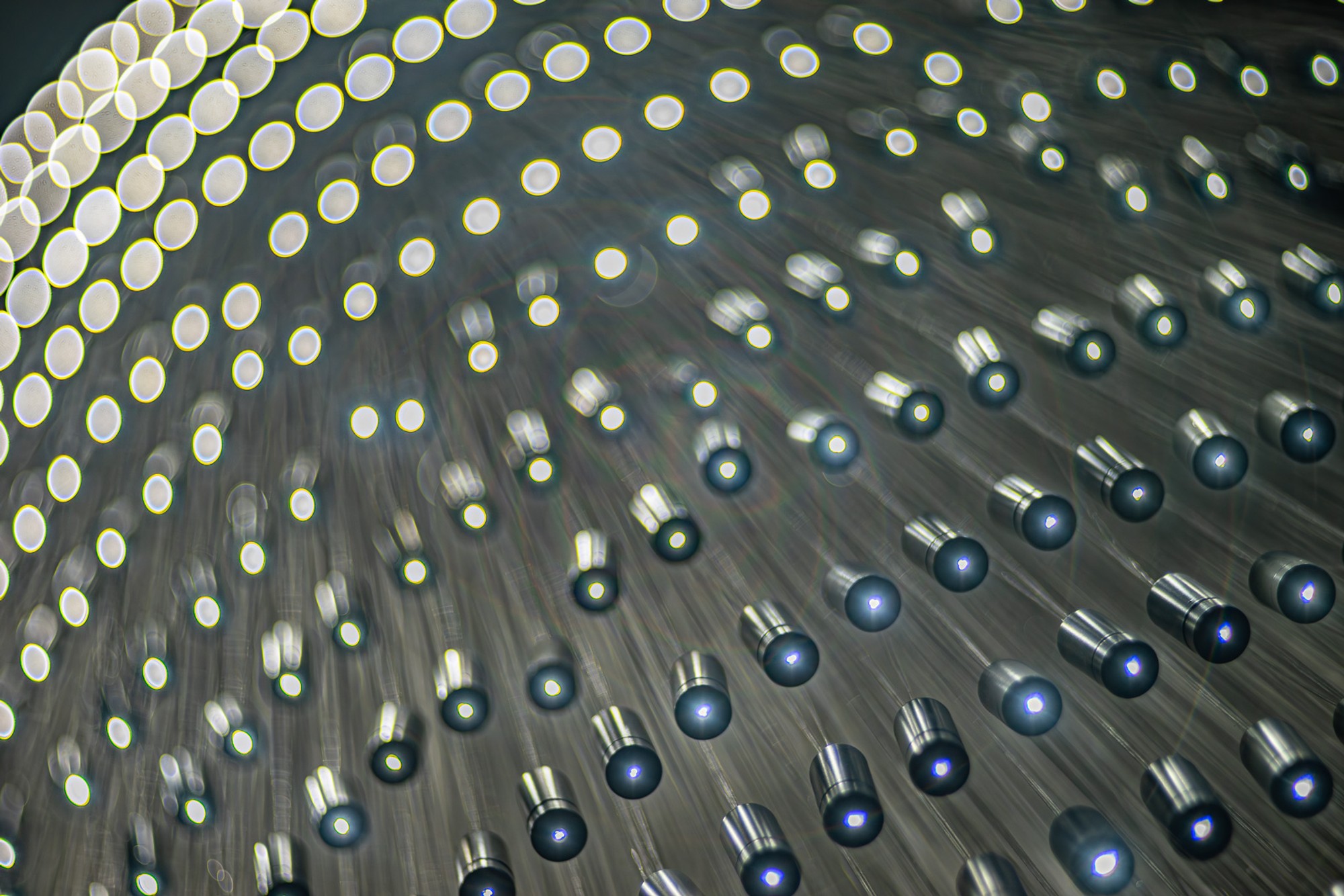 Hundreds of small LEDs suspended on individual wires at varying heights from a Parisian ceiling, photographed from directly below. The aggregate reads as a single luminous cloud