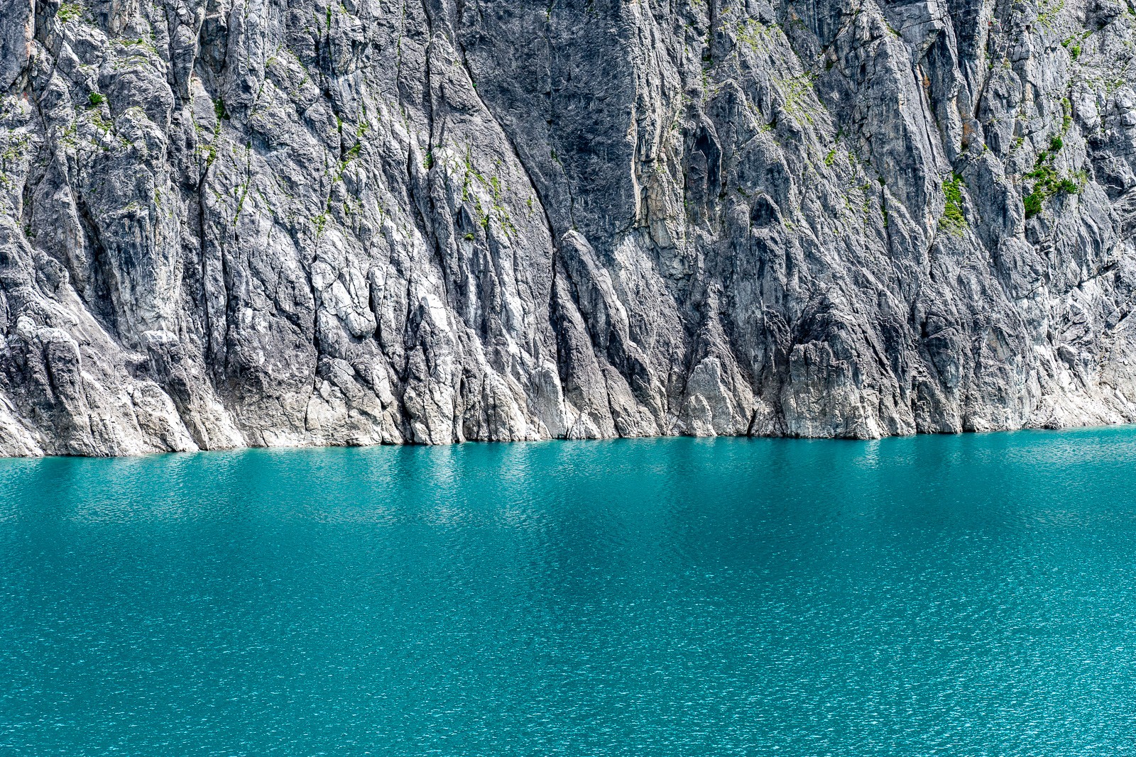 A glacial lake in the Austrian Alps where sheer rock faces meet turquoise water with almost no shoreline between them. Shot in the brief window before afternoon winds arrive, the surface holds everything in perfect stillness.