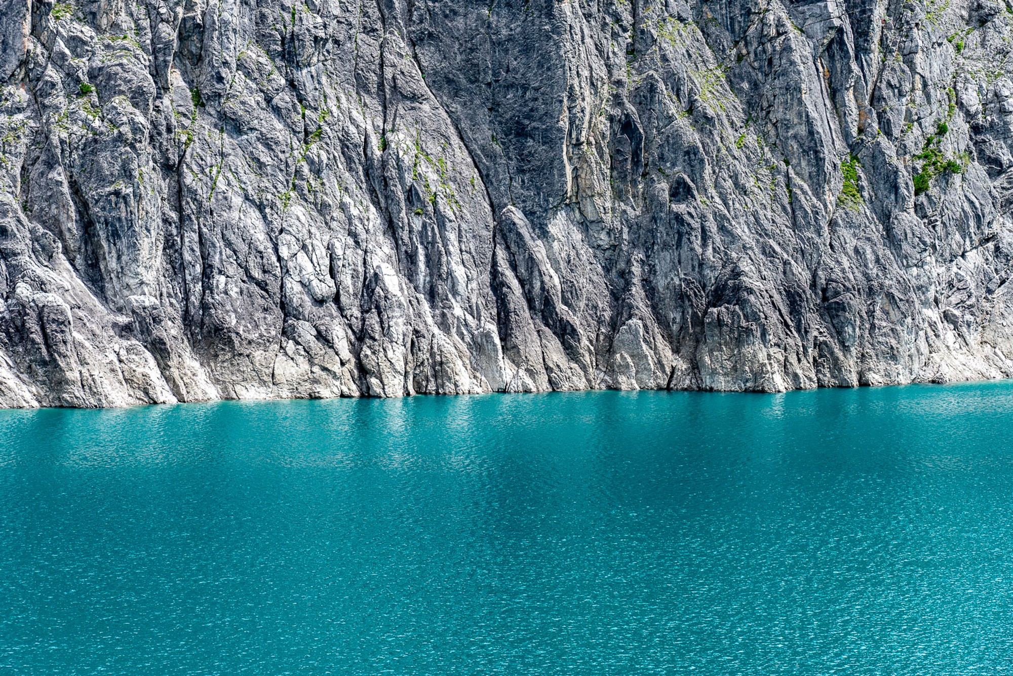 A glacial lake in the Austrian Alps where sheer rock faces meet turquoise water with almost no shoreline between them. Shot in the brief window before afternoon winds arrive, the surface holds everything in perfect stillness.