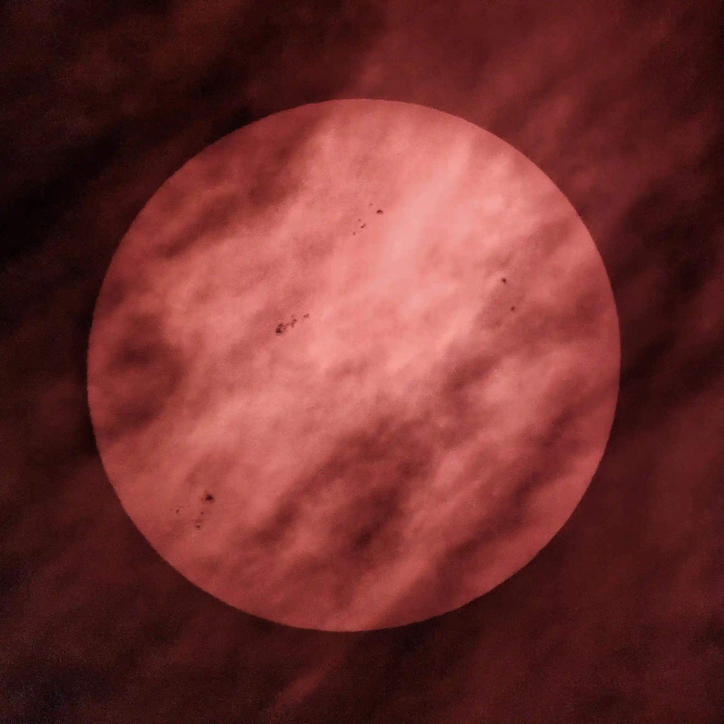 Zon met vele vlekken deels zichtbaar achter de wolken