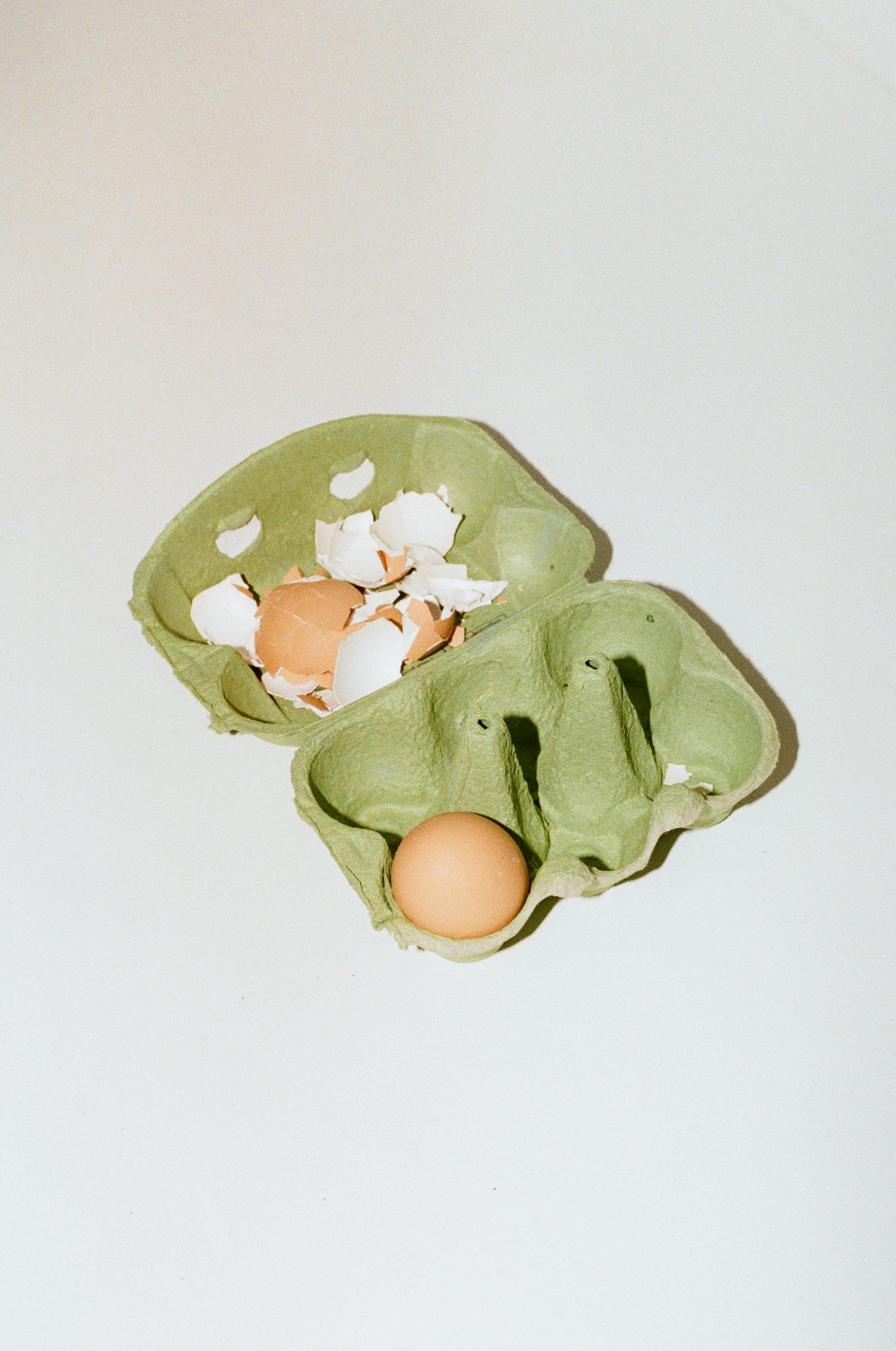 A broken egg shell in a carton on an office kitchen bench