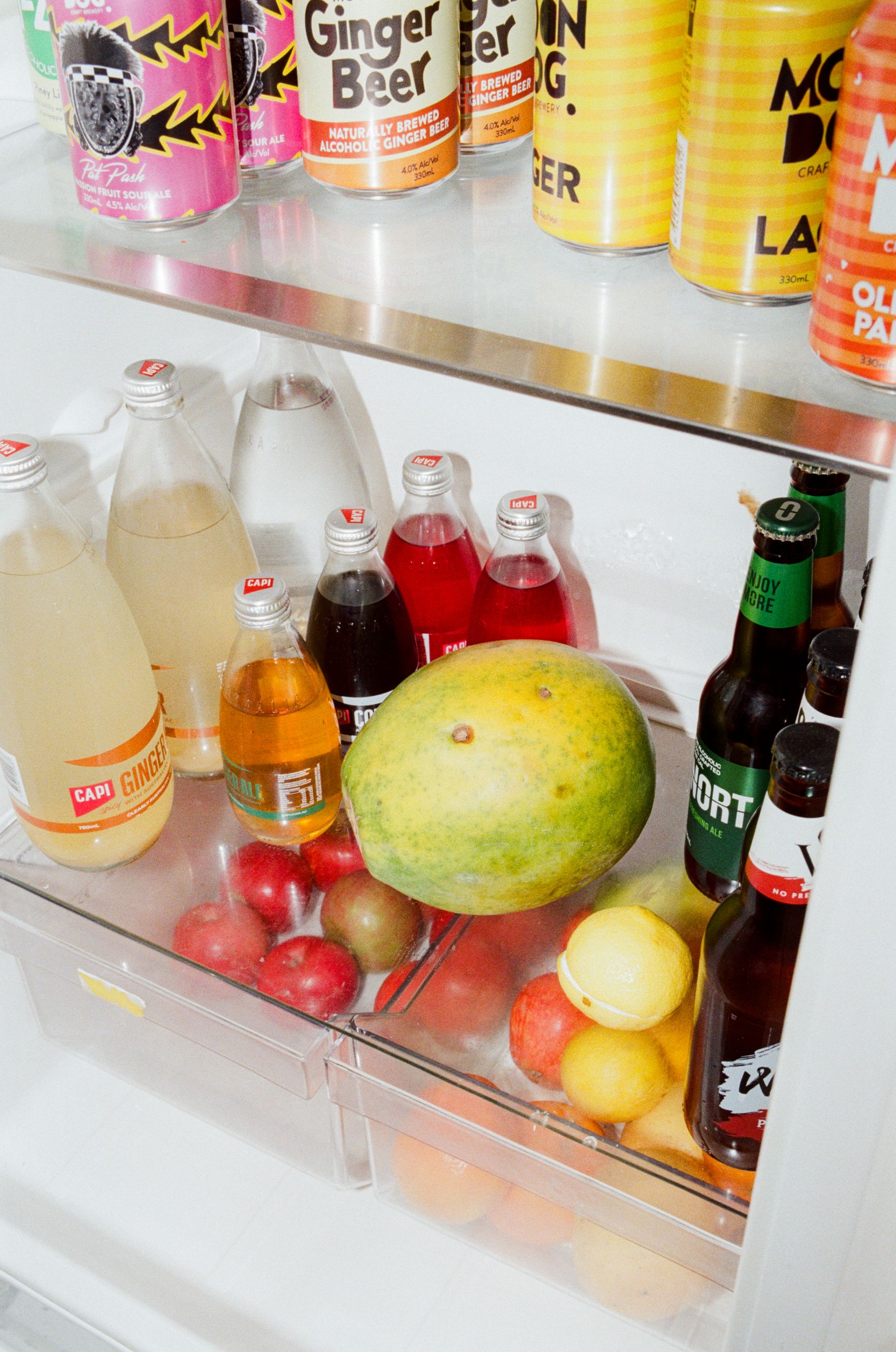 A close up of the interior of an office fridge filled with drinks and fruit