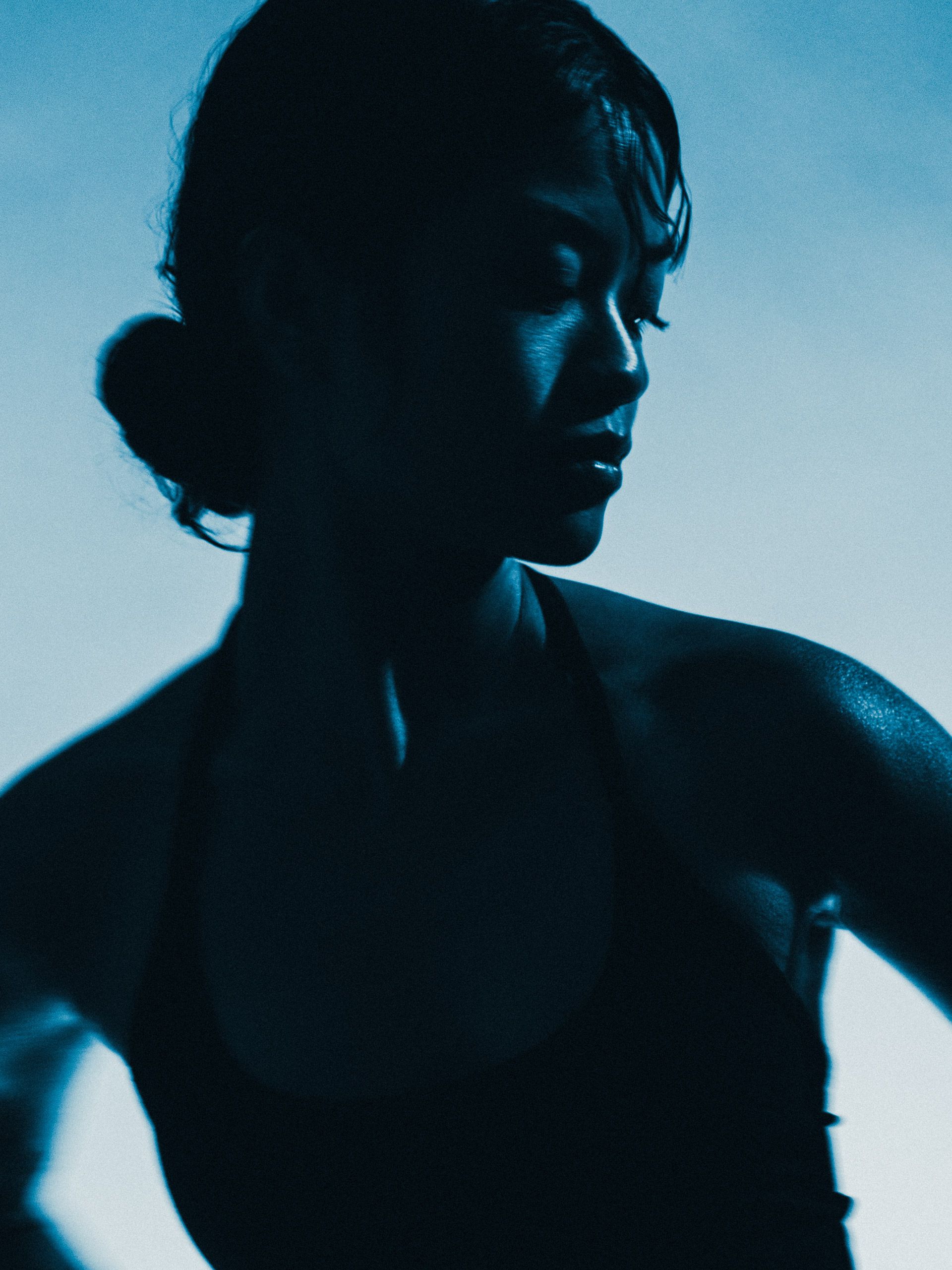 Side-lit portrait against a blue background.