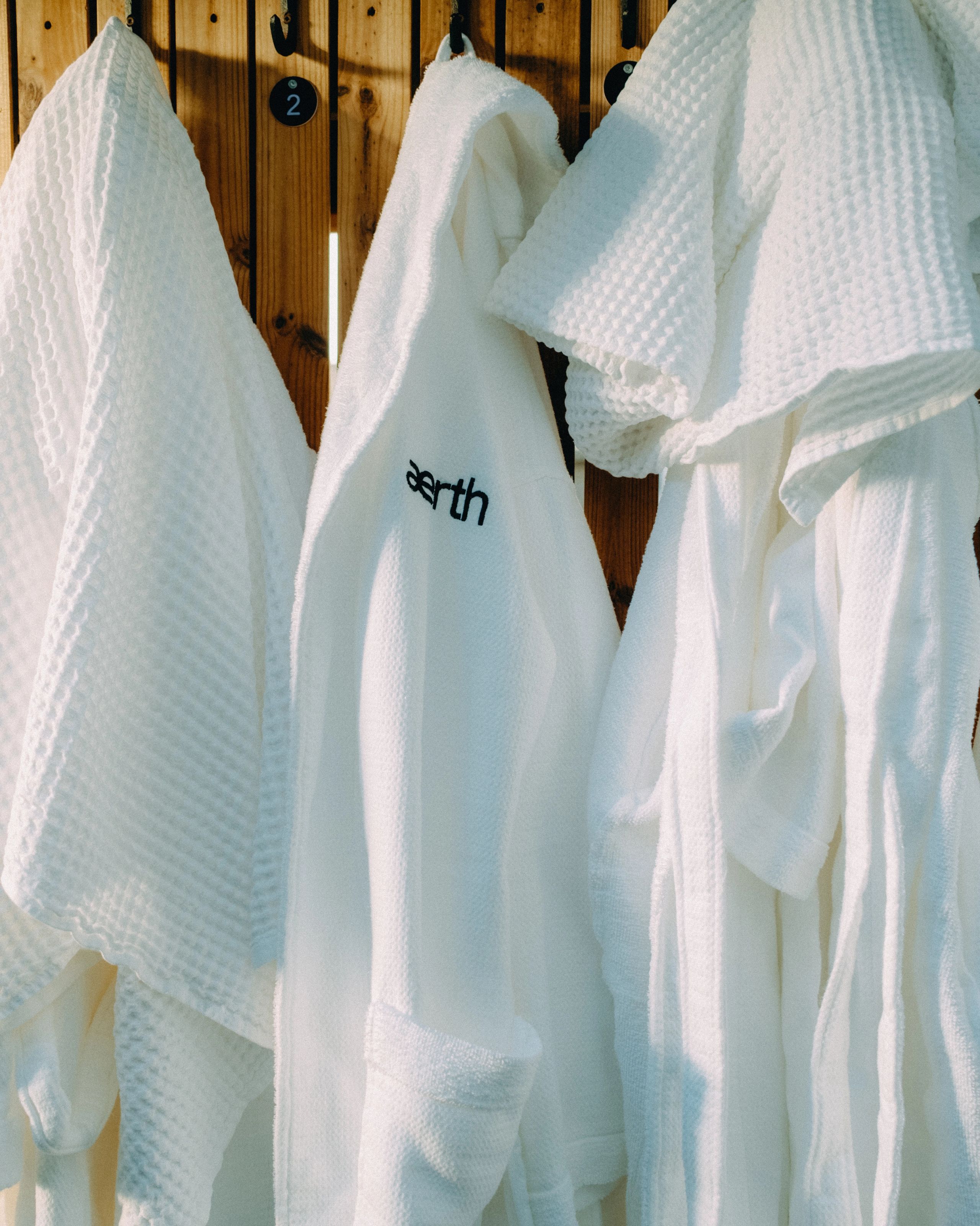 White Aerth robes hanging beside the sauna.