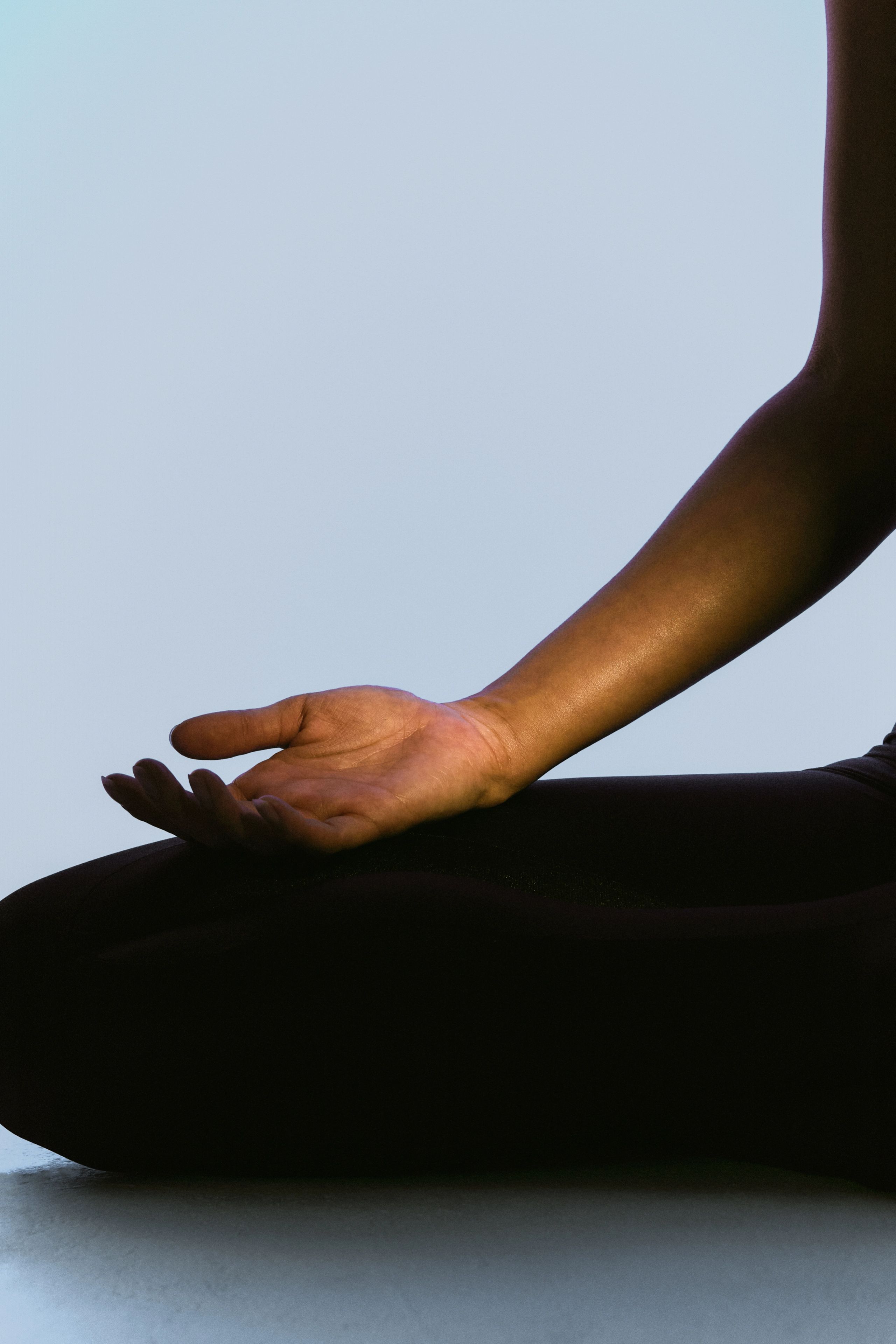 Open hand resting on a seated figure's knee.