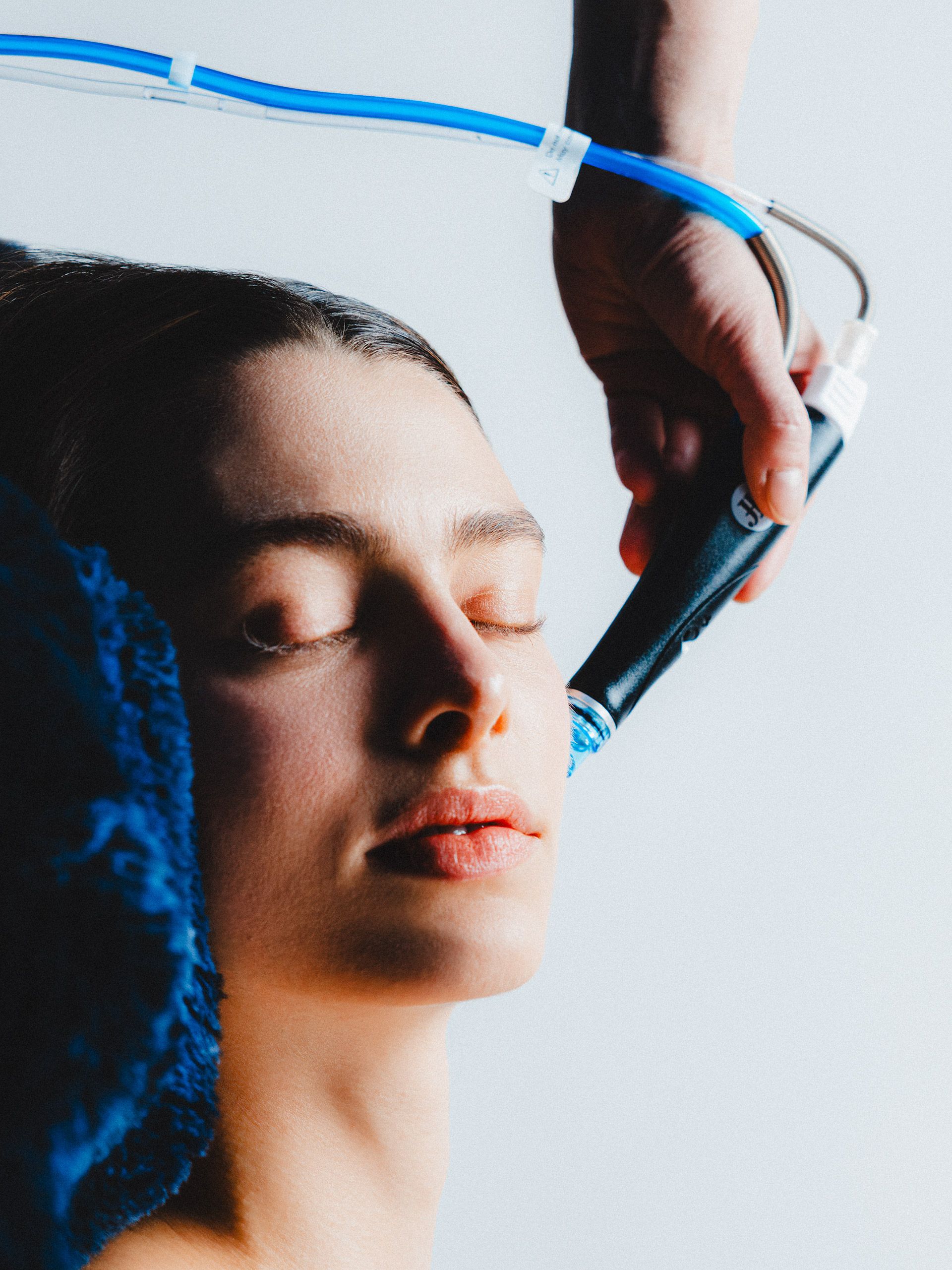 Close-up of a facial treatment with a blue-tubed handpiece.