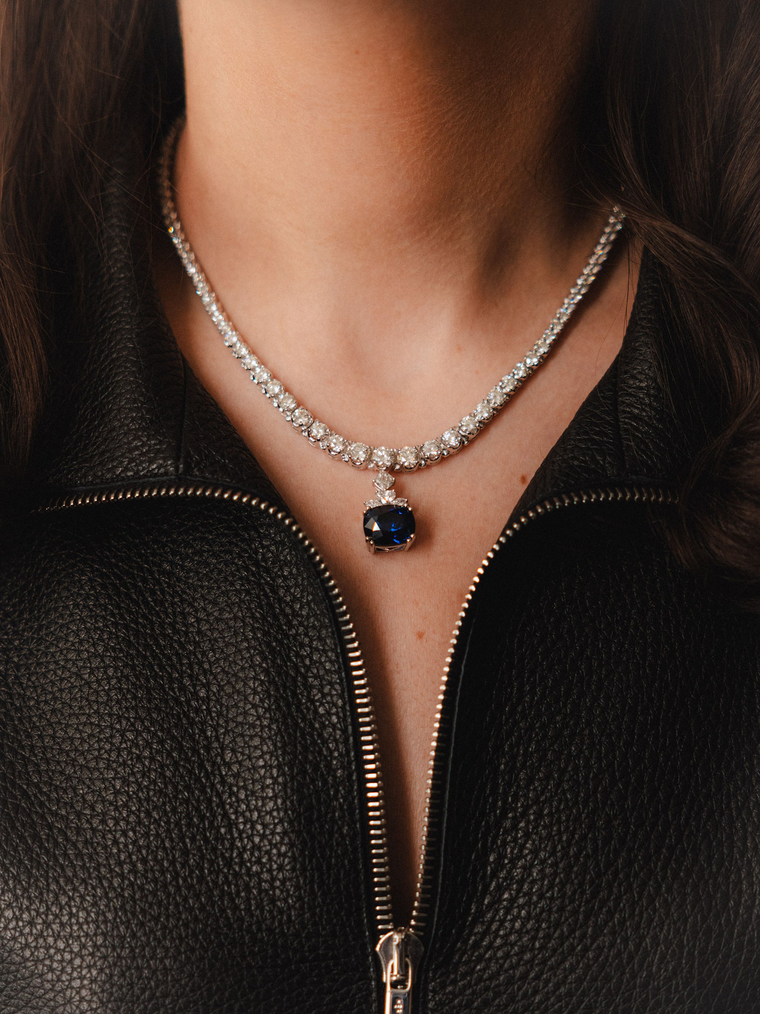 Sapphire pendant necklace worn with a black zippered top.
