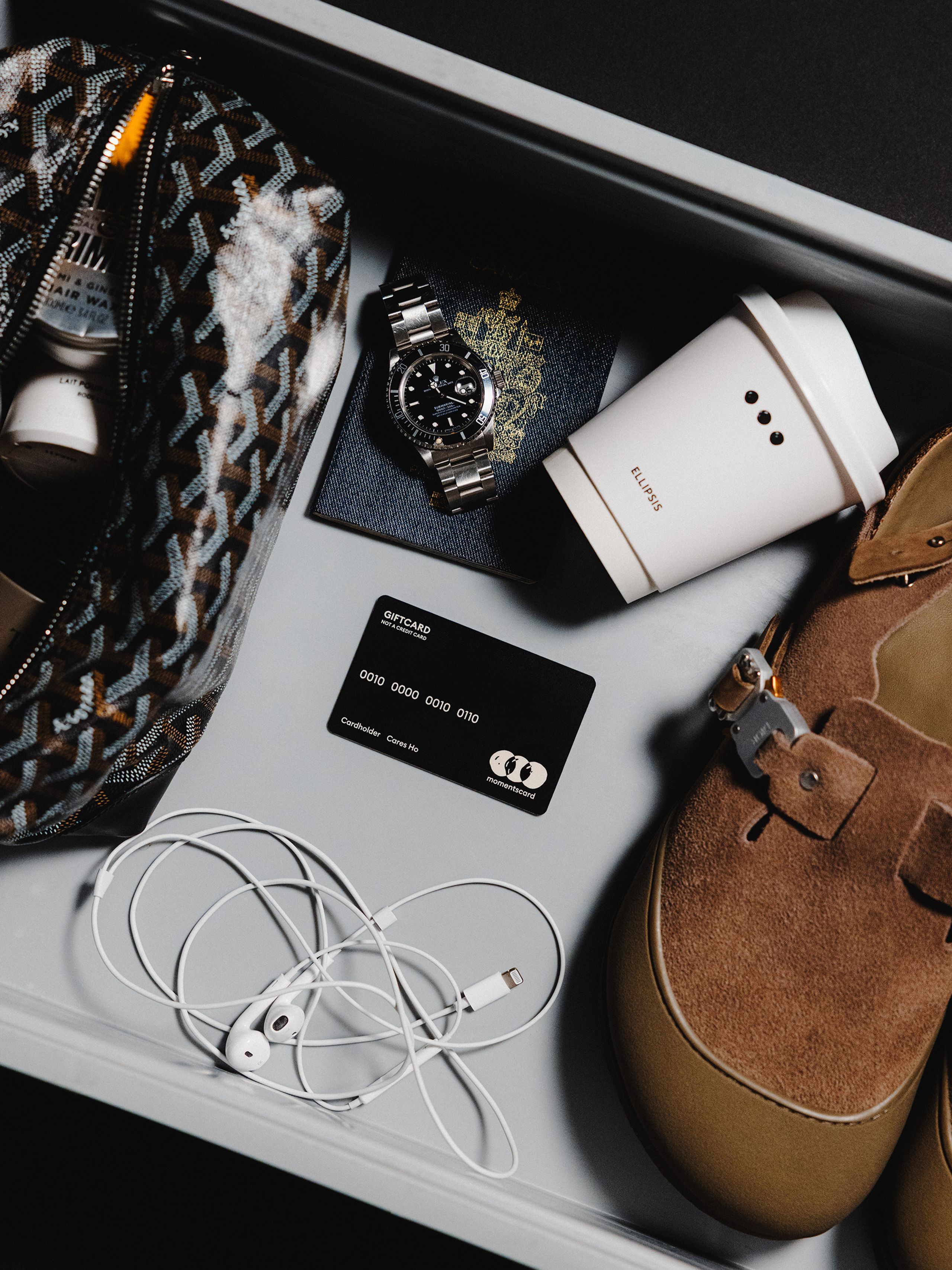 Ellipsis gift card arranged with a bag, headphones, and personal accessories.