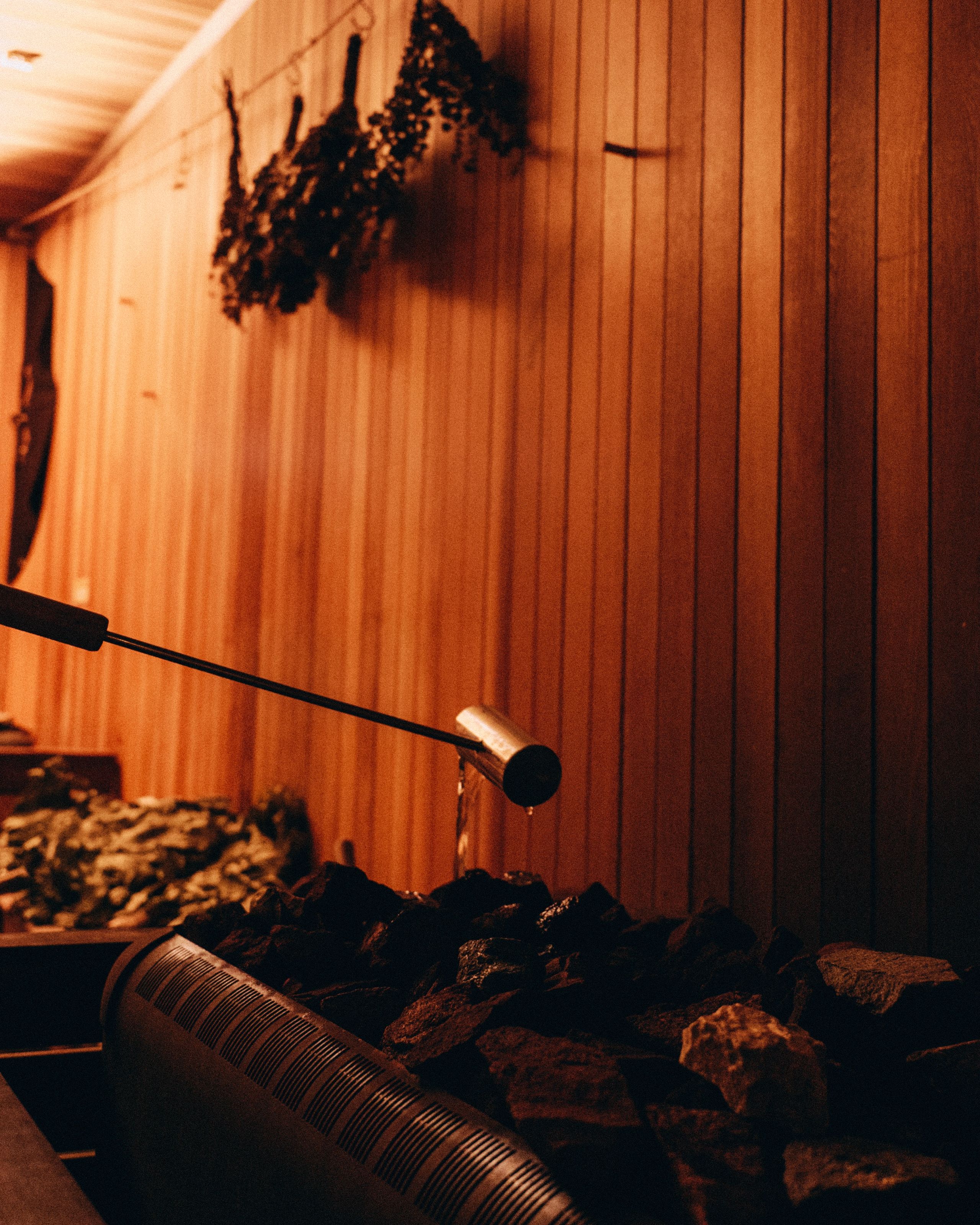 Water ladle held above the heater stones in an AetherHaus sauna.
