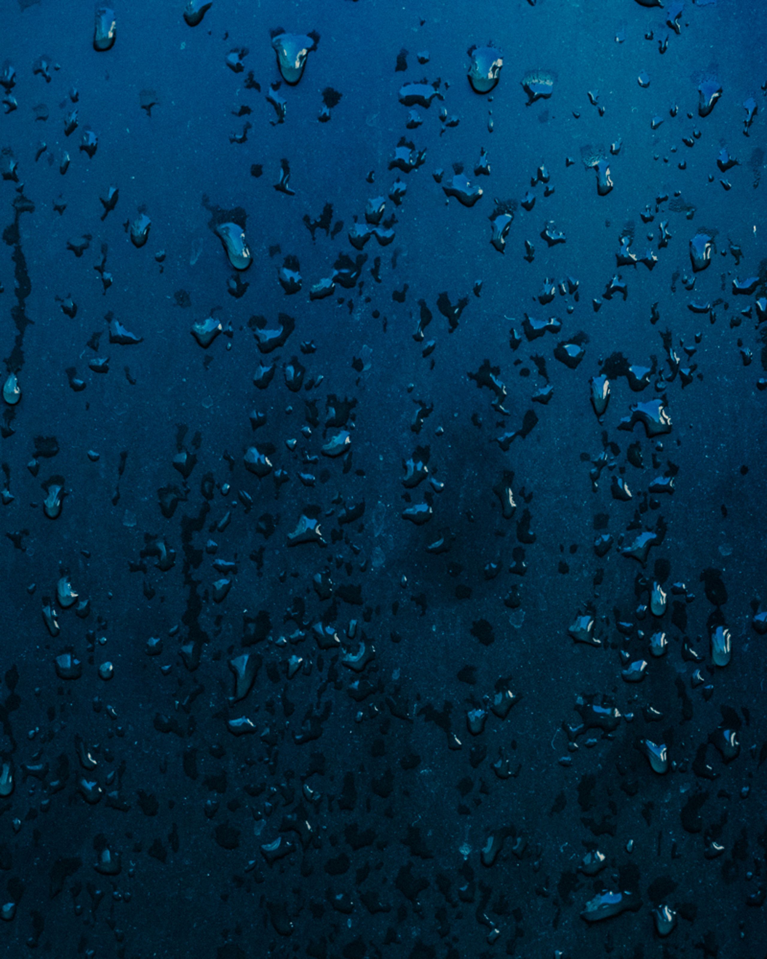 Water droplets on a deep blue surface at Aerth.