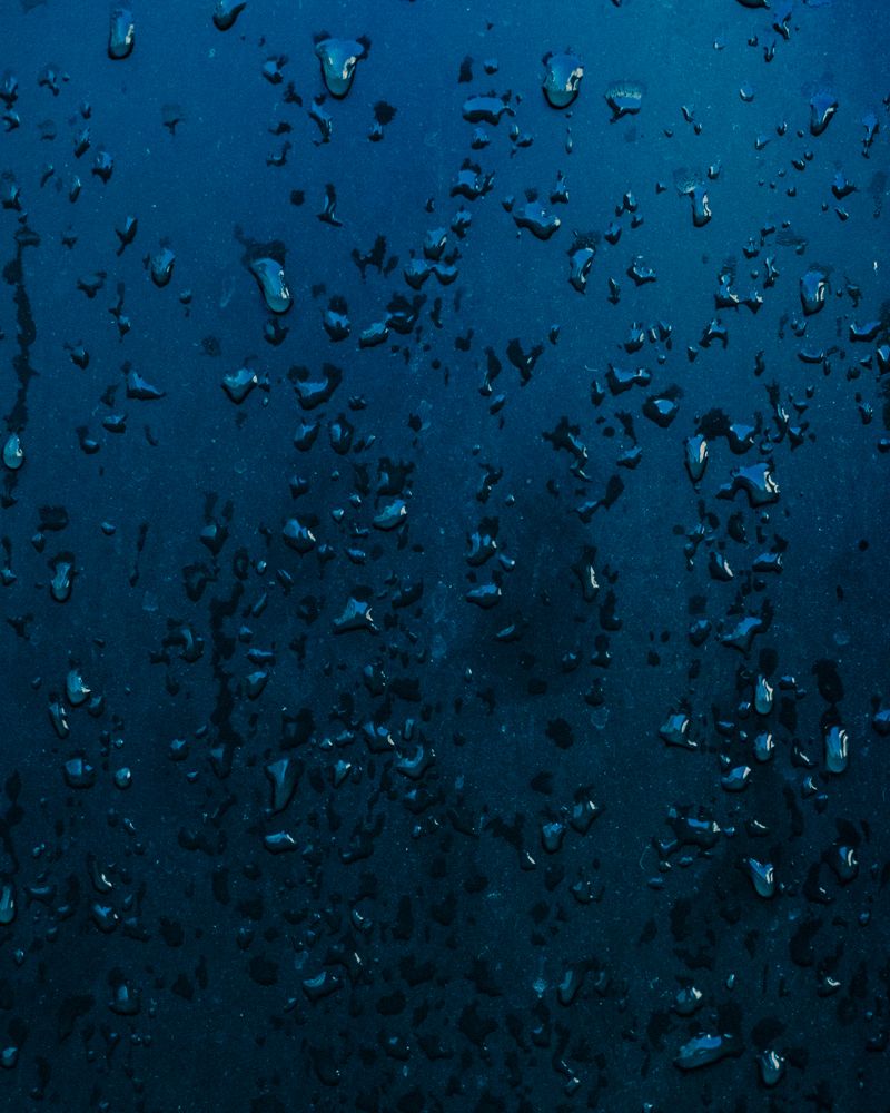Water droplets on a deep blue surface at Aerth.