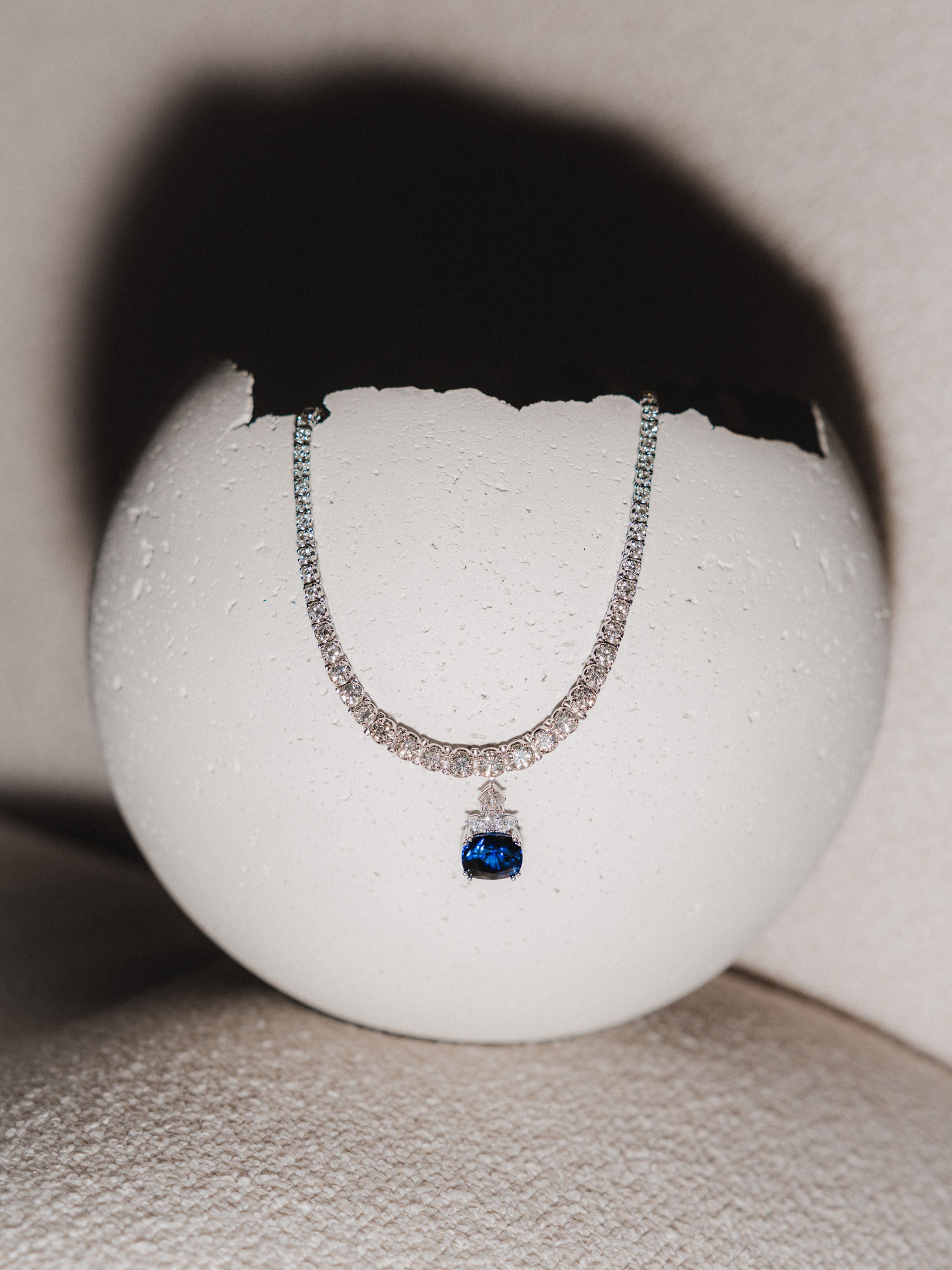 Pendant necklace displayed on a white rounded object.