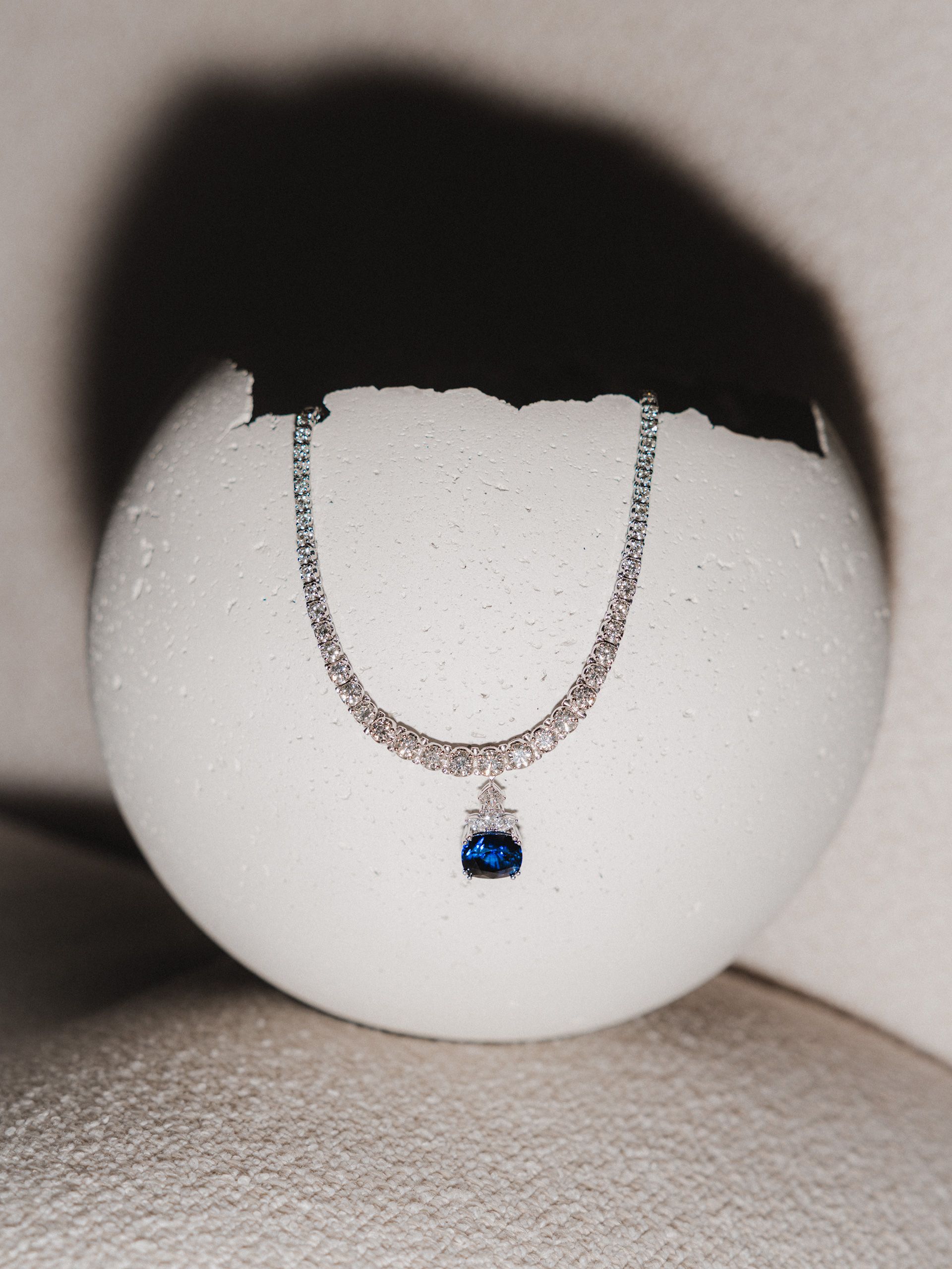 Pendant necklace displayed on a white rounded object.
