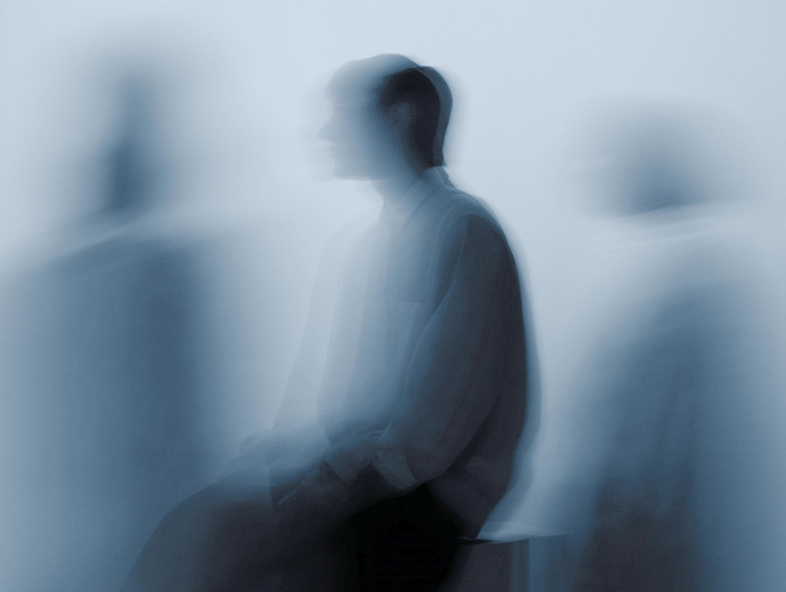 Blurred seated silhouettes in soft blue light.