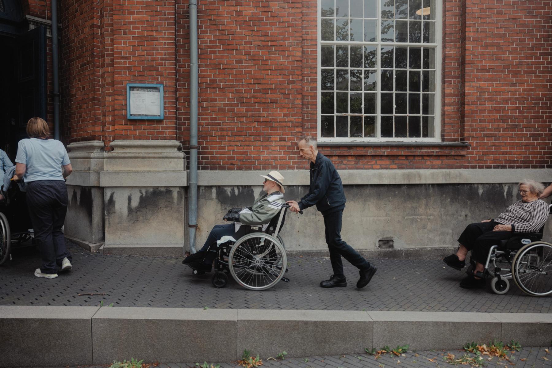 Mand går med person i kørestol
