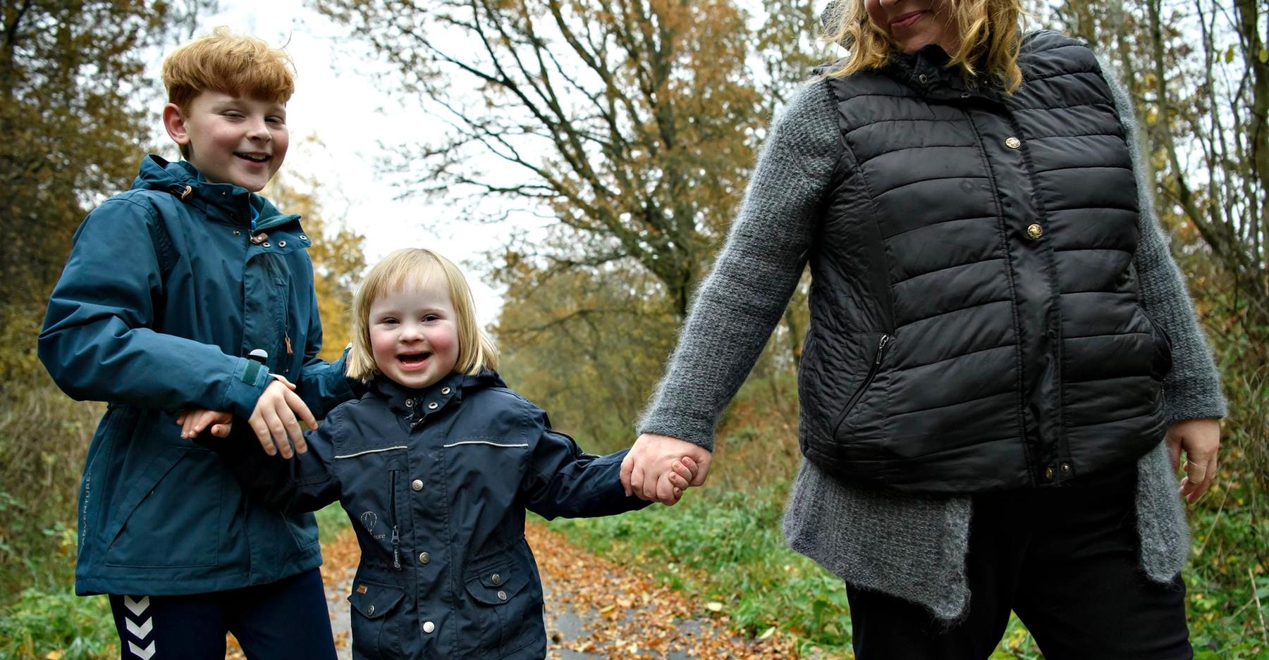 Mor holder i hånd med sine to børn