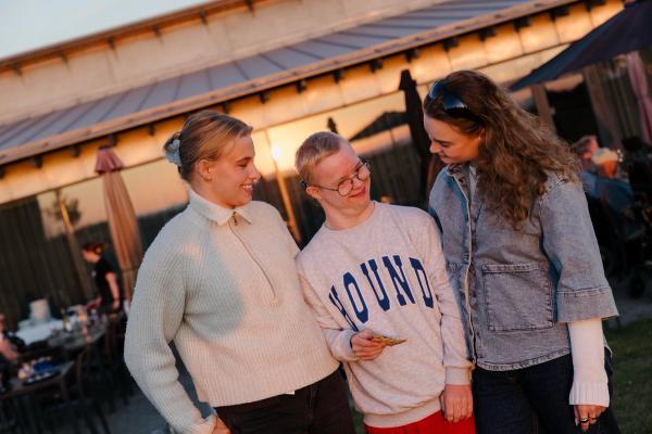 Tre unge står sammen og griner