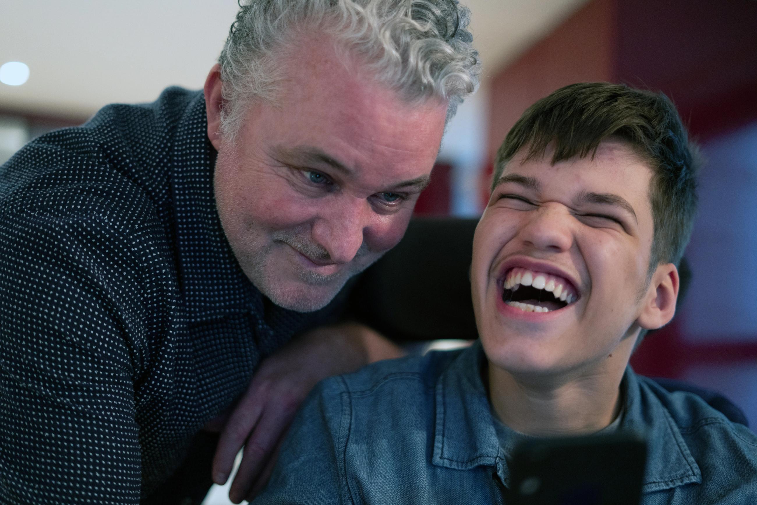 Søn viser far noget sjovt på sin telefon