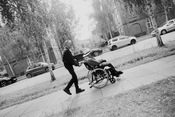 Mand går med person i kørestol